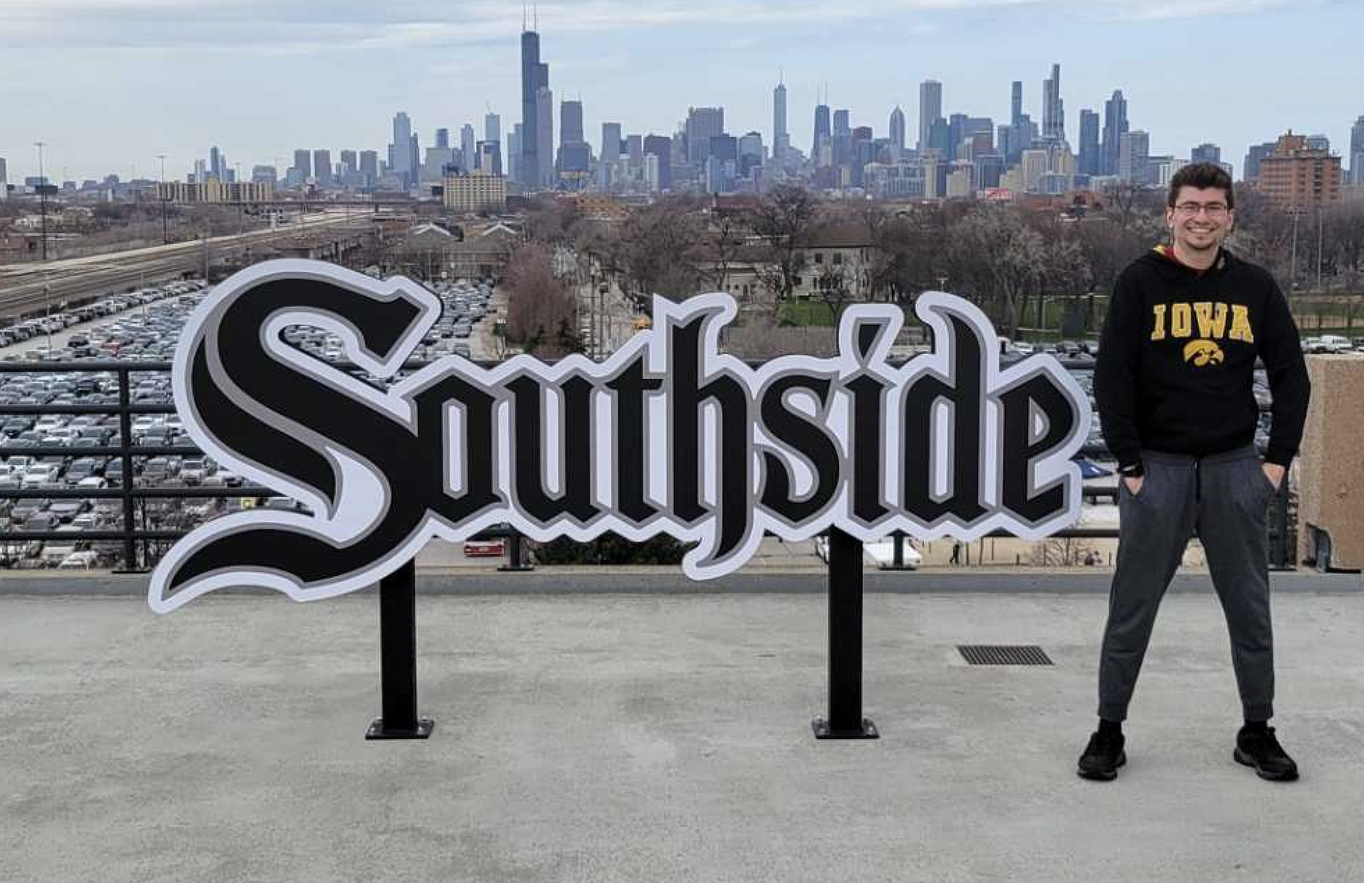 A man in an Iowa sweater poses next to a large sign that says, "Southside."
