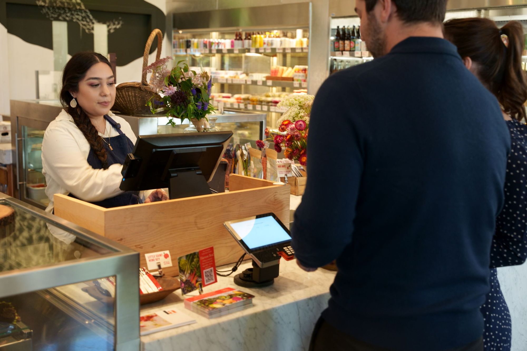 A restaurant cashier rings up an order for a couple at a counter-service restaurant