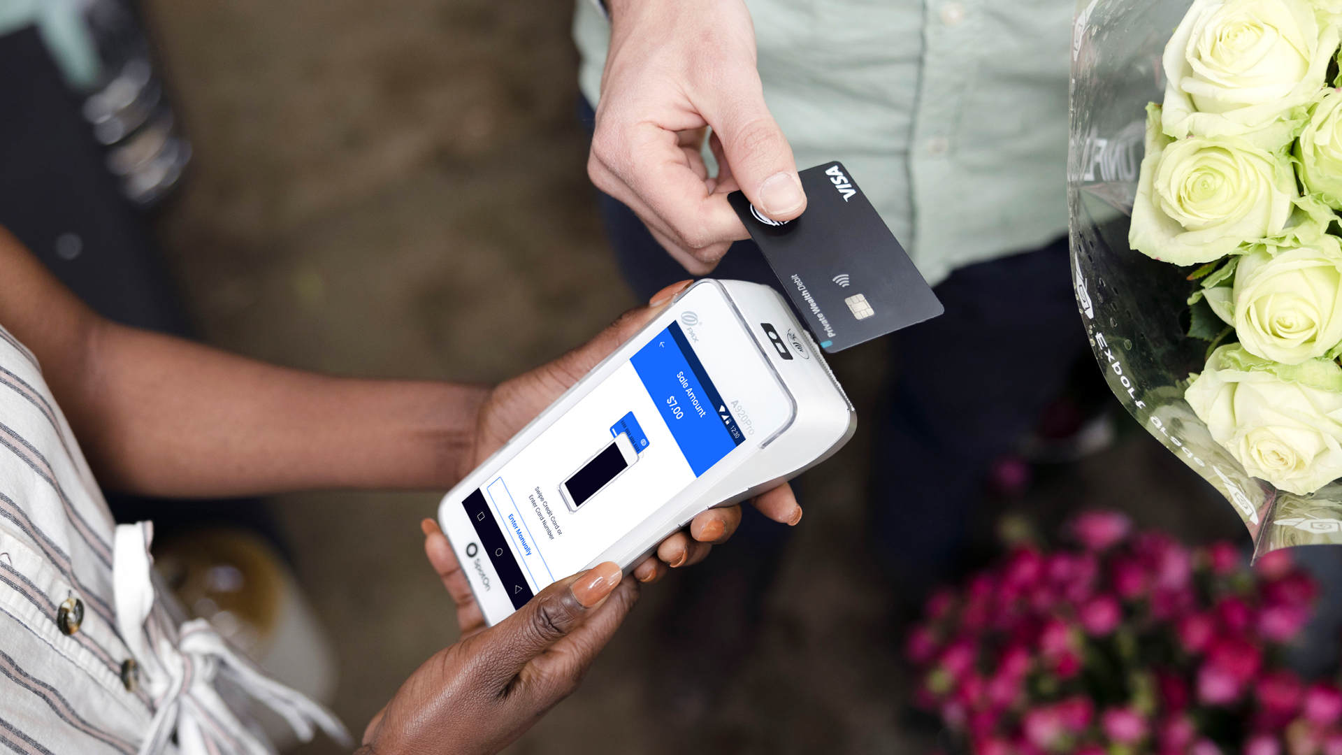 A customer taps their credit card to pay on a handheld retail POS device