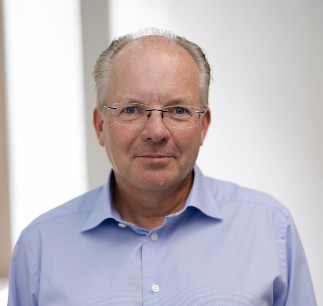 A man in glasses wears a blue button-up shirt.