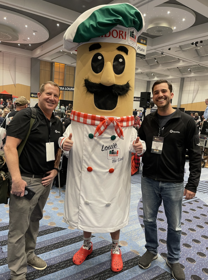 Two men pose in front of a mascot.