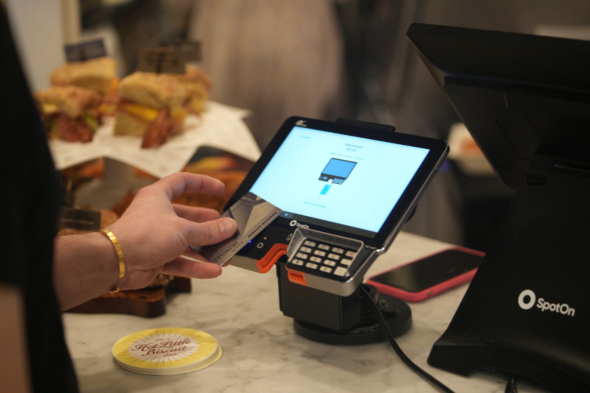 Restaurant guest presses their credit card against a point-of-sale terminal to make a purchase.