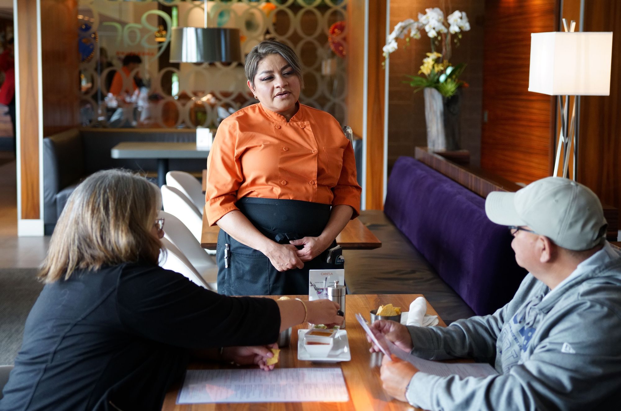 A server takes an order from two seated guests at Mesero restaurant