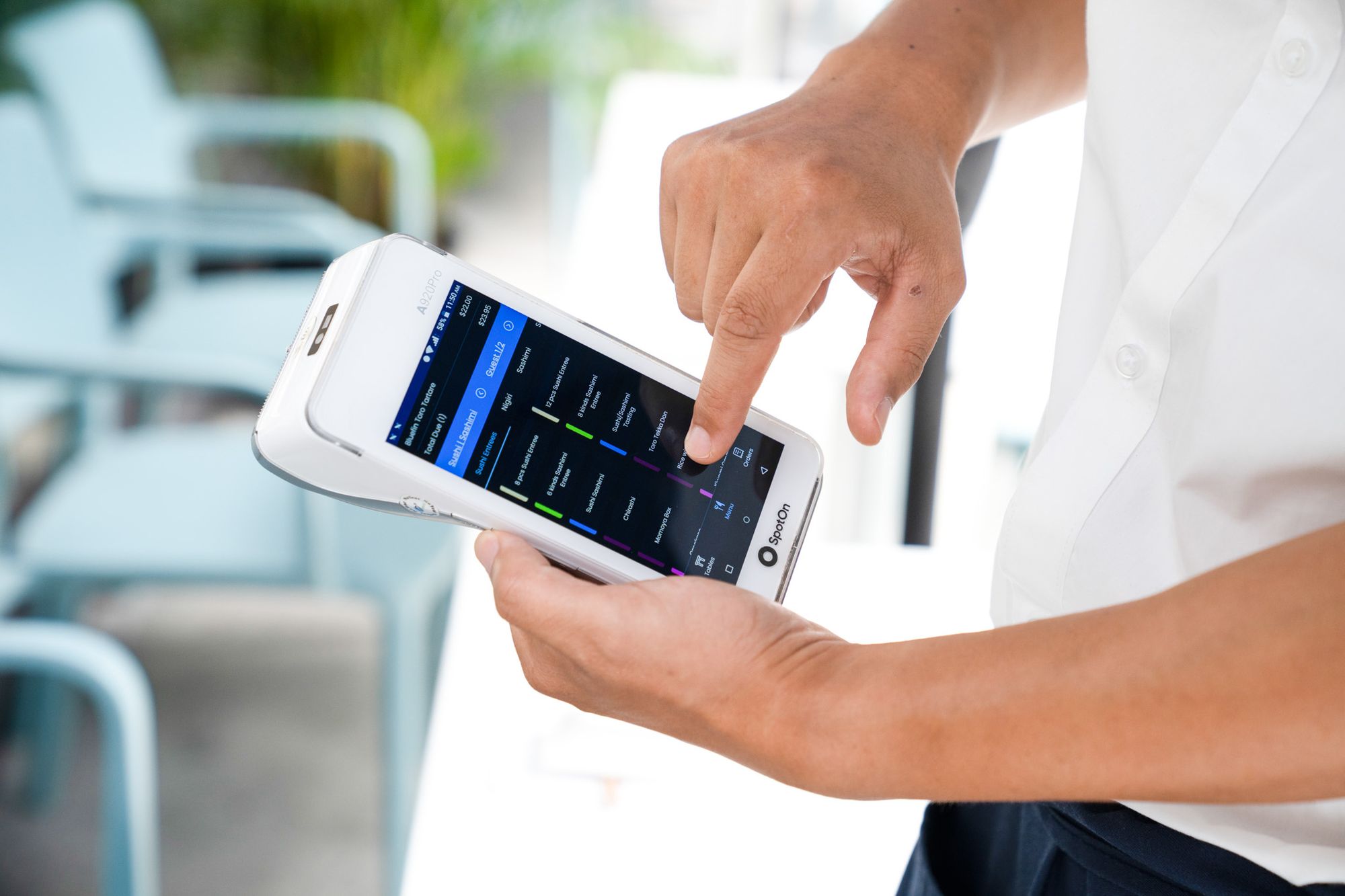 Restaurant staff points to a SpotOn handheld point-of-sale device.