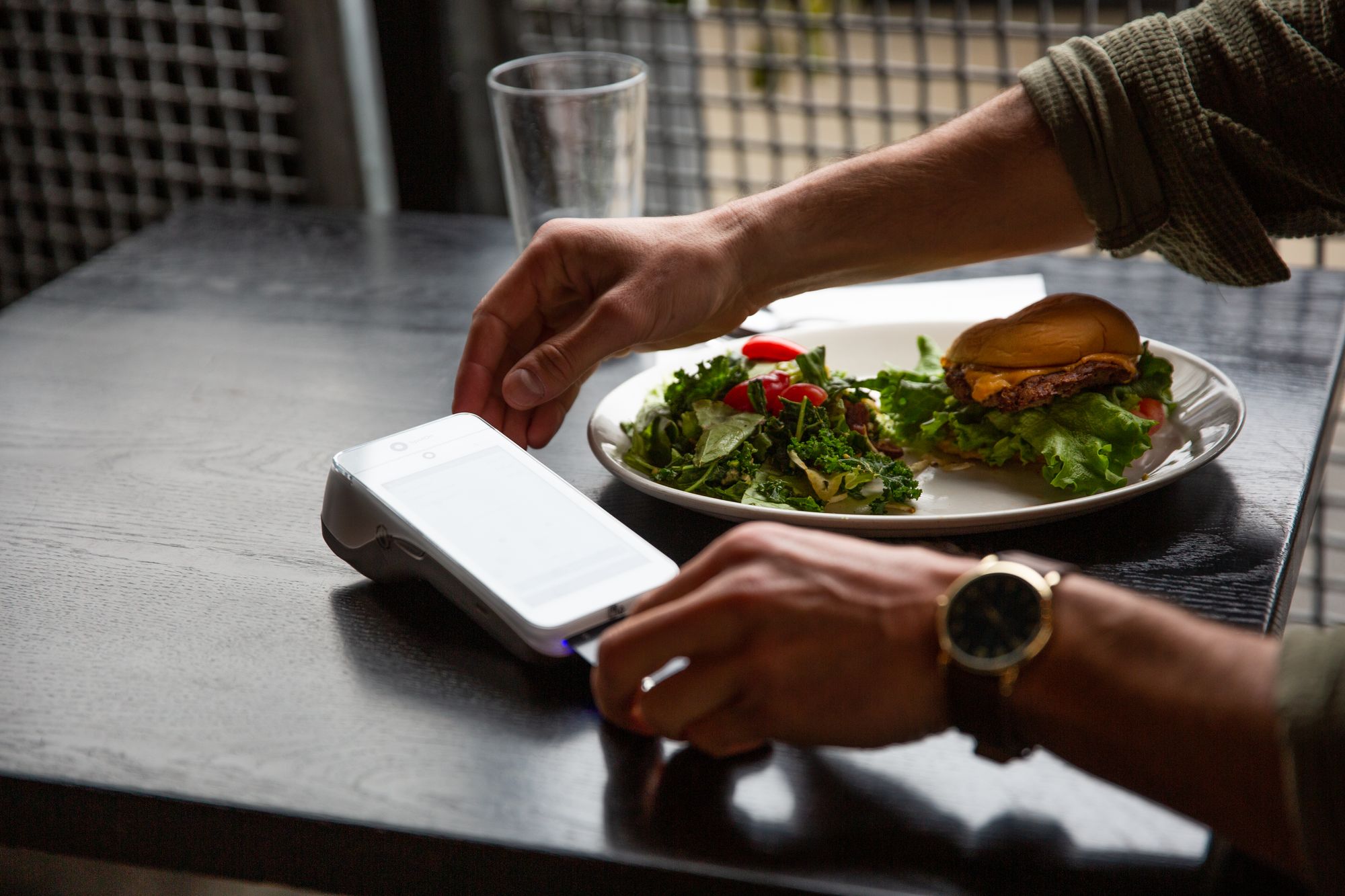 Person at restaurant completing a transaction through a handheld device.