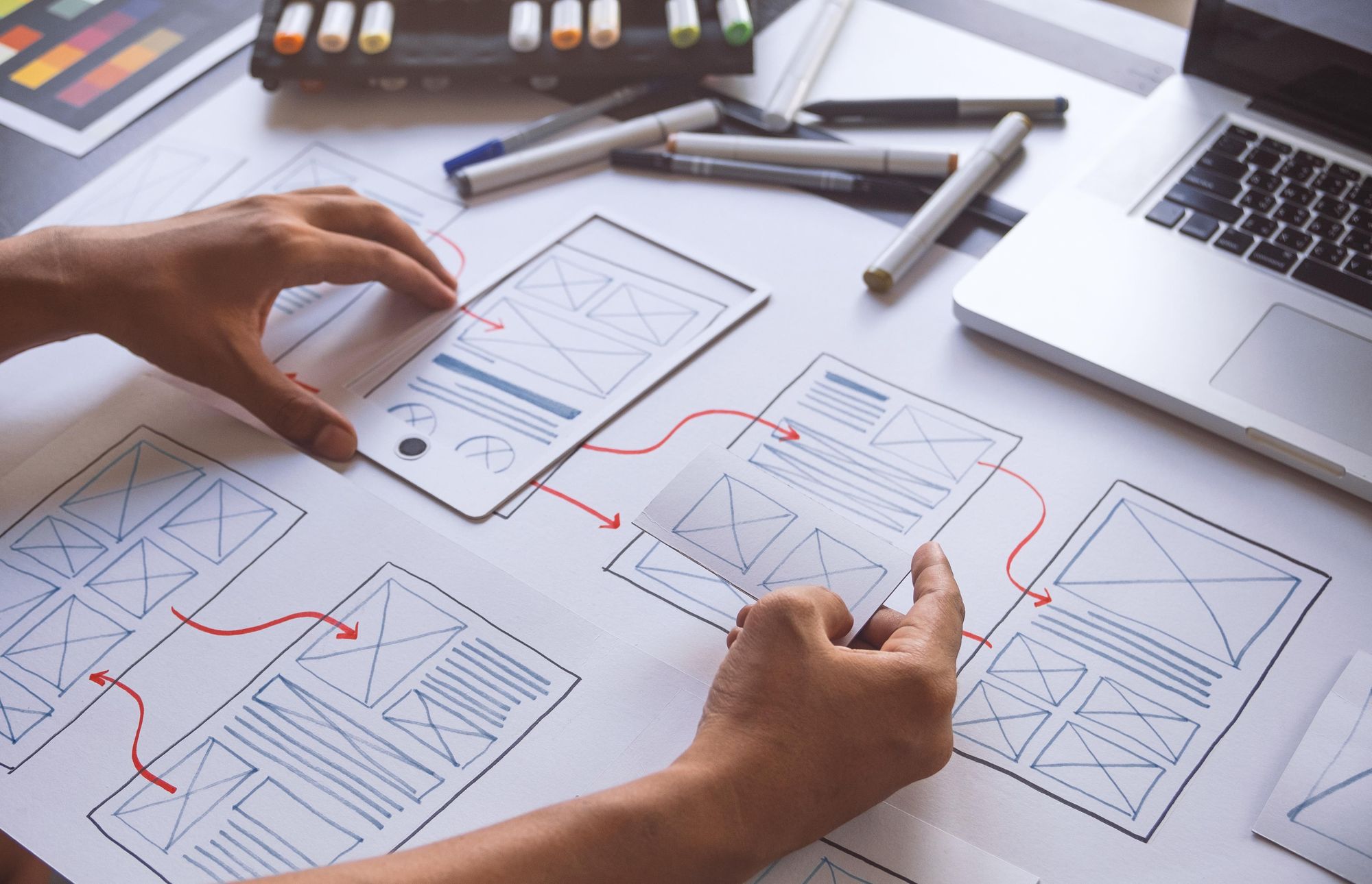 Person at a desk with layout plans for building a website.