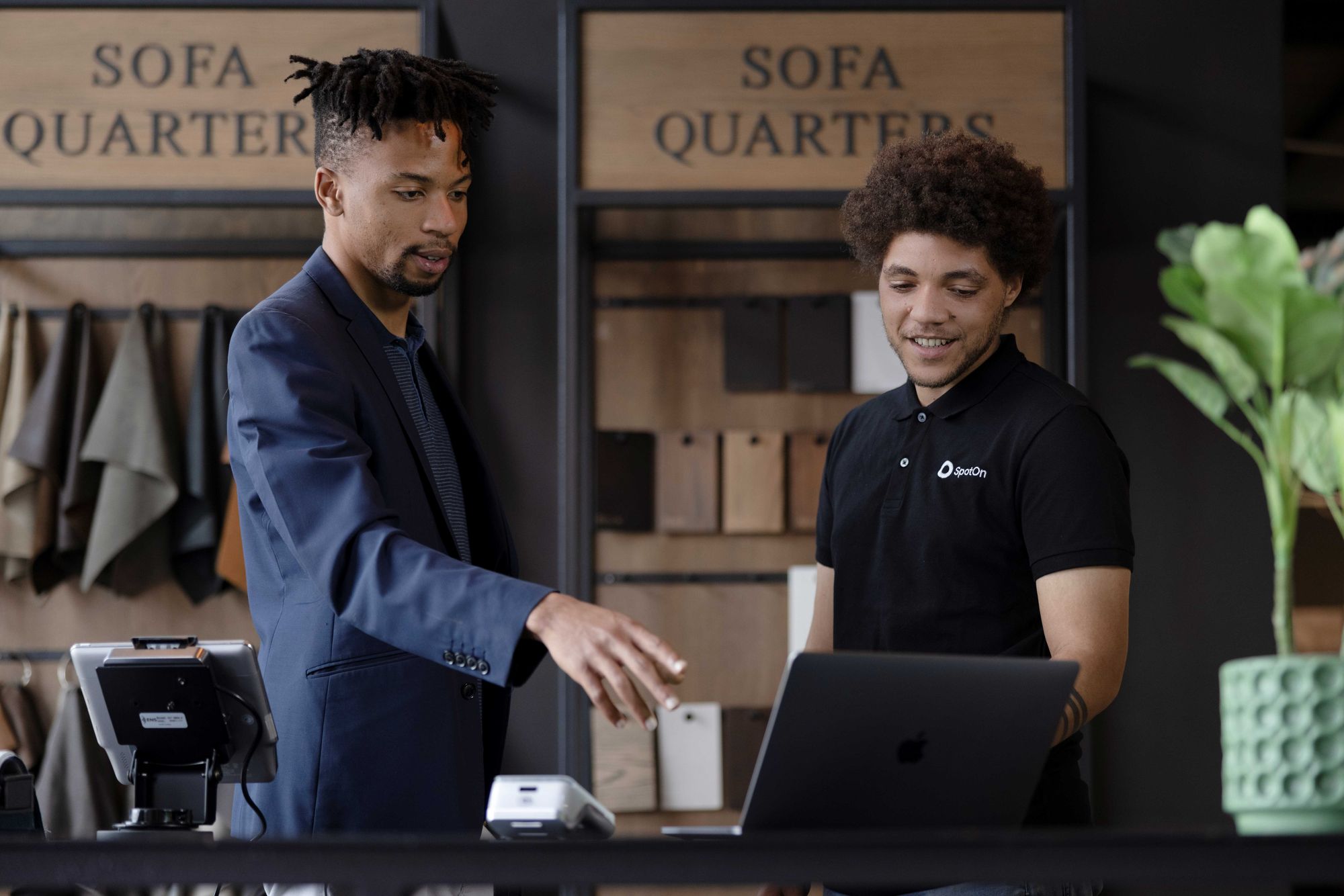 A SpotOn representative shows a shop owner how to view their online dashboard on a laptop computer