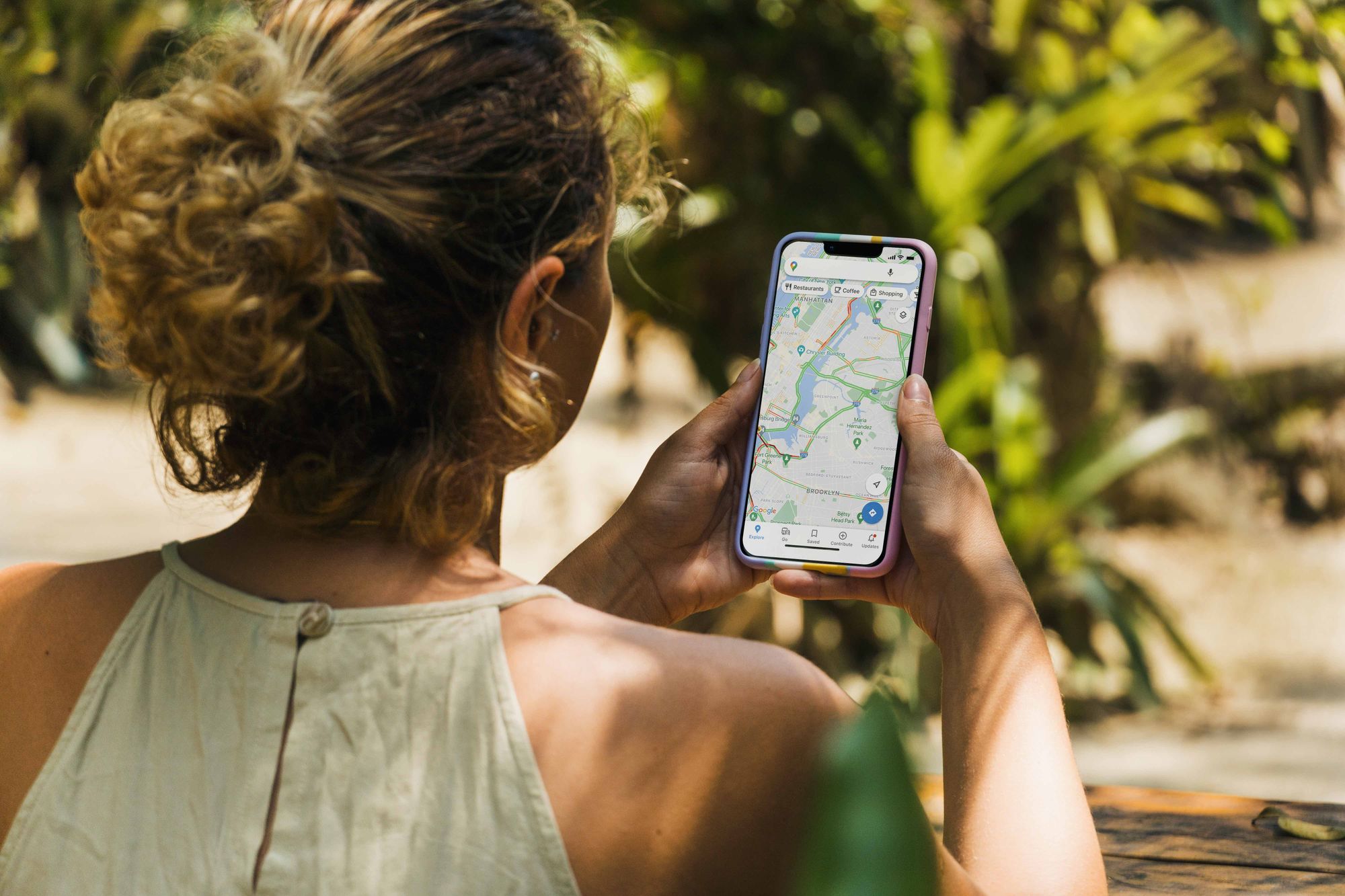 Woman at a park searches for a restaurnat on Google Maps.