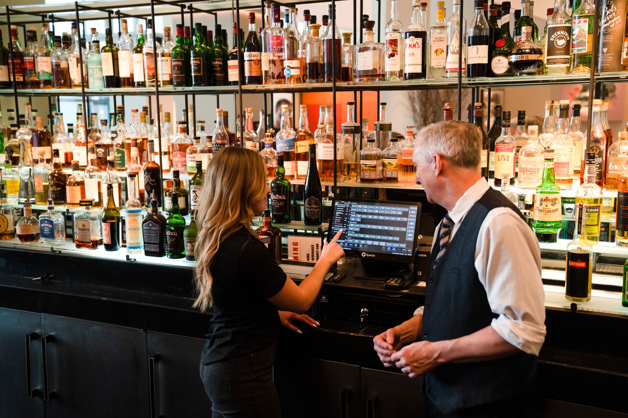 A POS representative shows a restaurant manager how to opearate the POS at their bar.