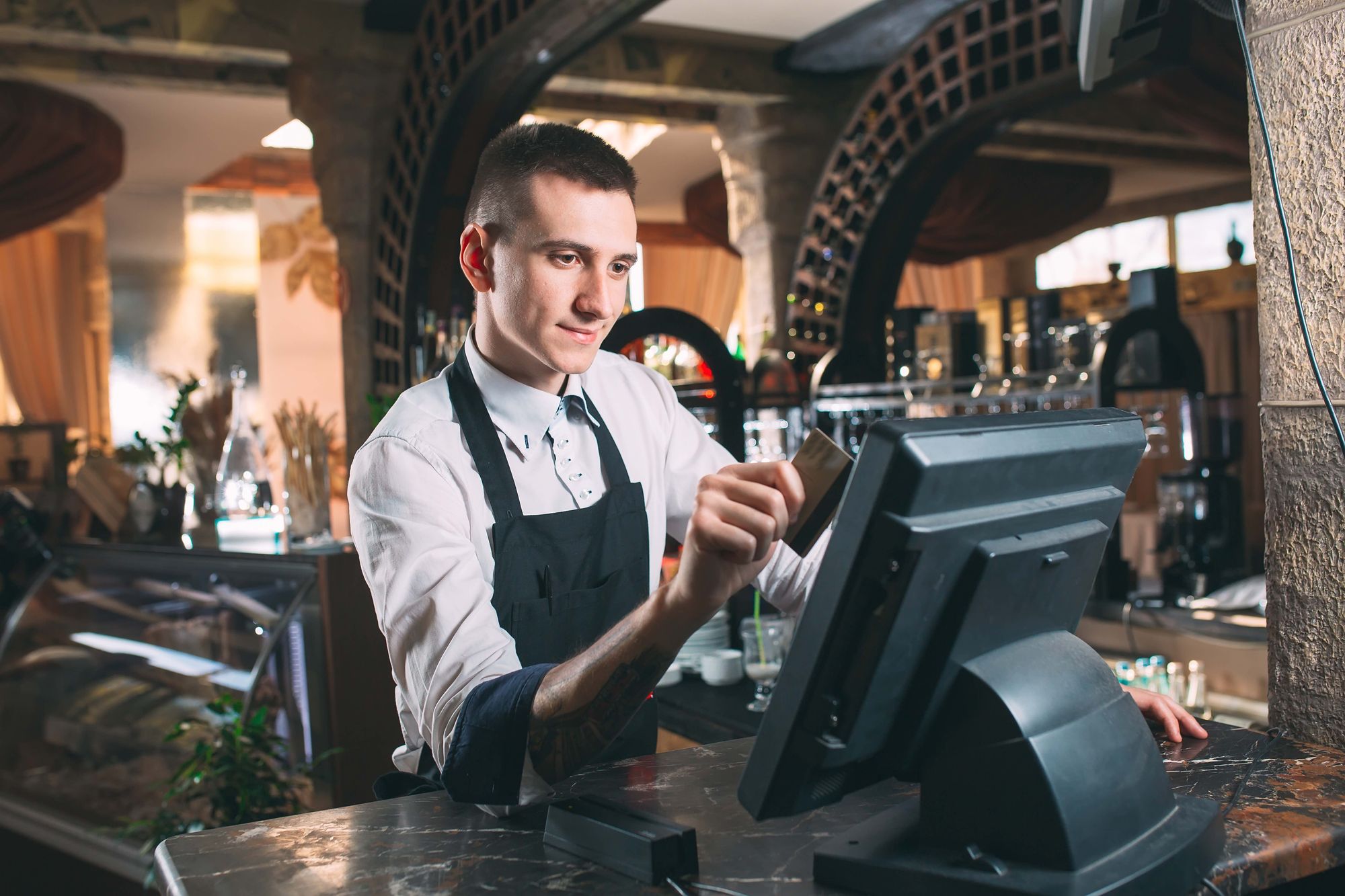 Male restaurant worker rings up an order at a point-of-sale station.