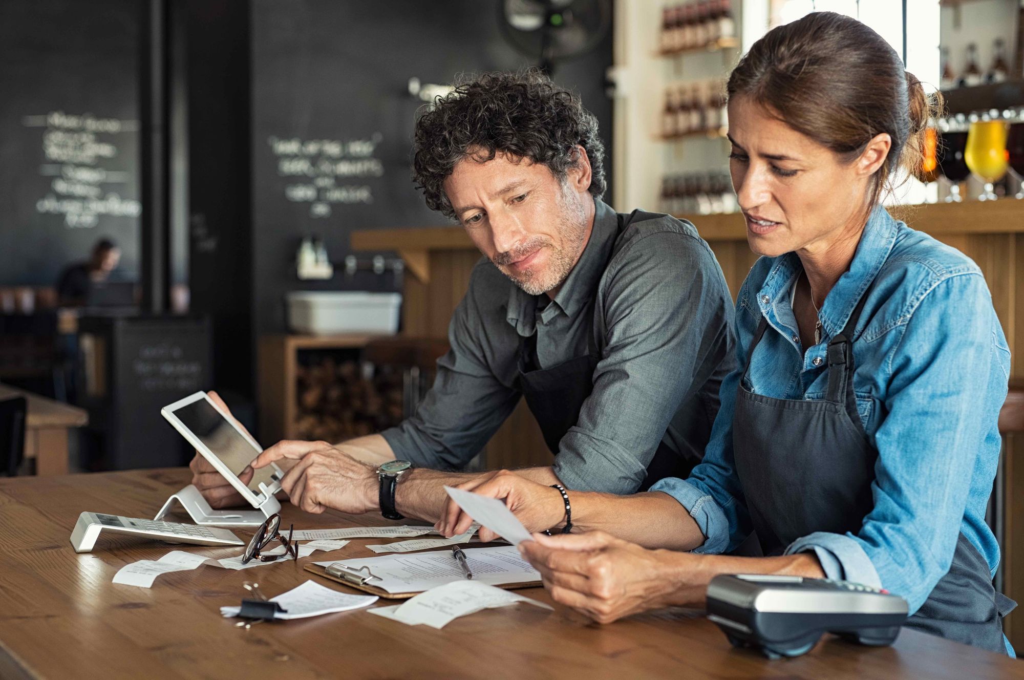 Man and woman restaurant owners calculate their expenses at a table.