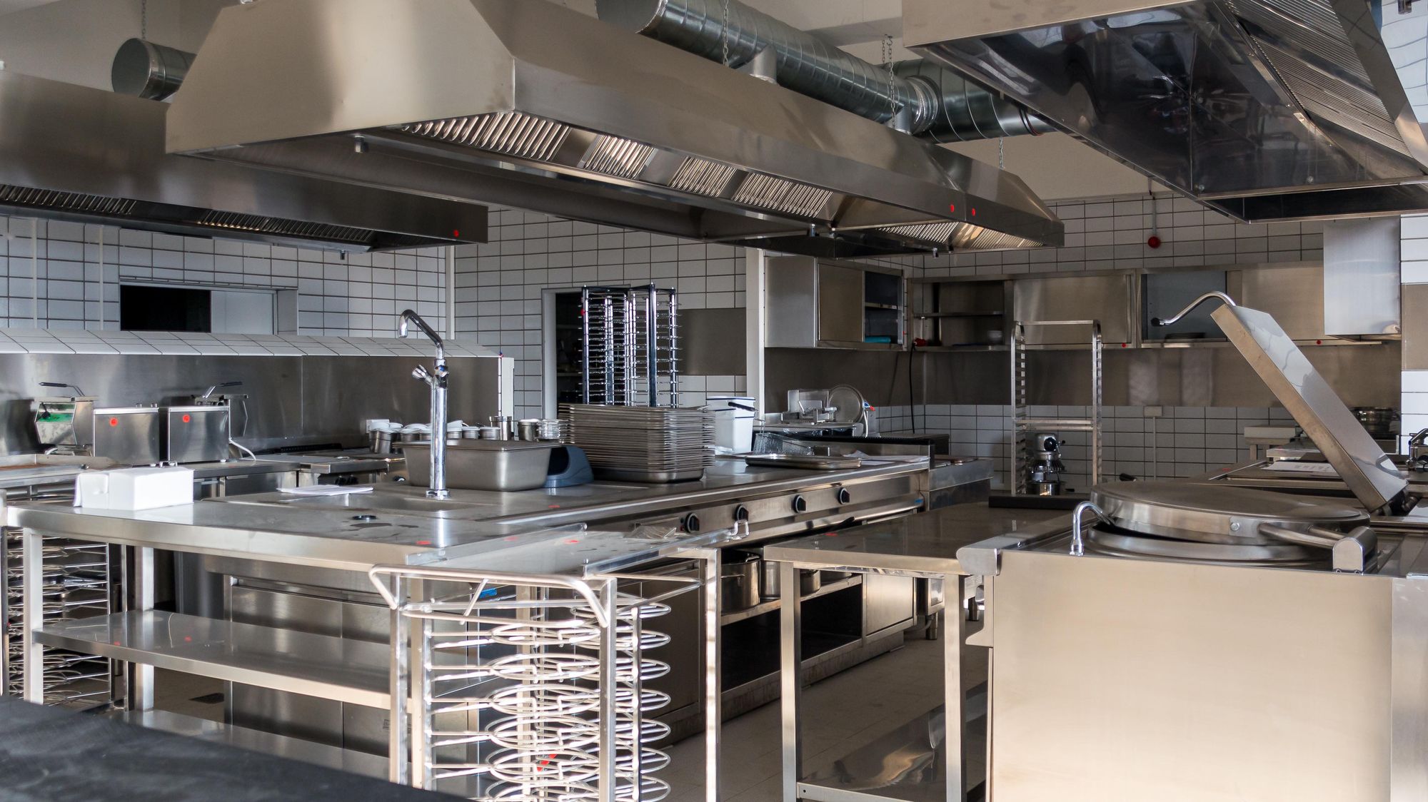 An empty restaurant kitchen that is set up with industrial grade equipment.