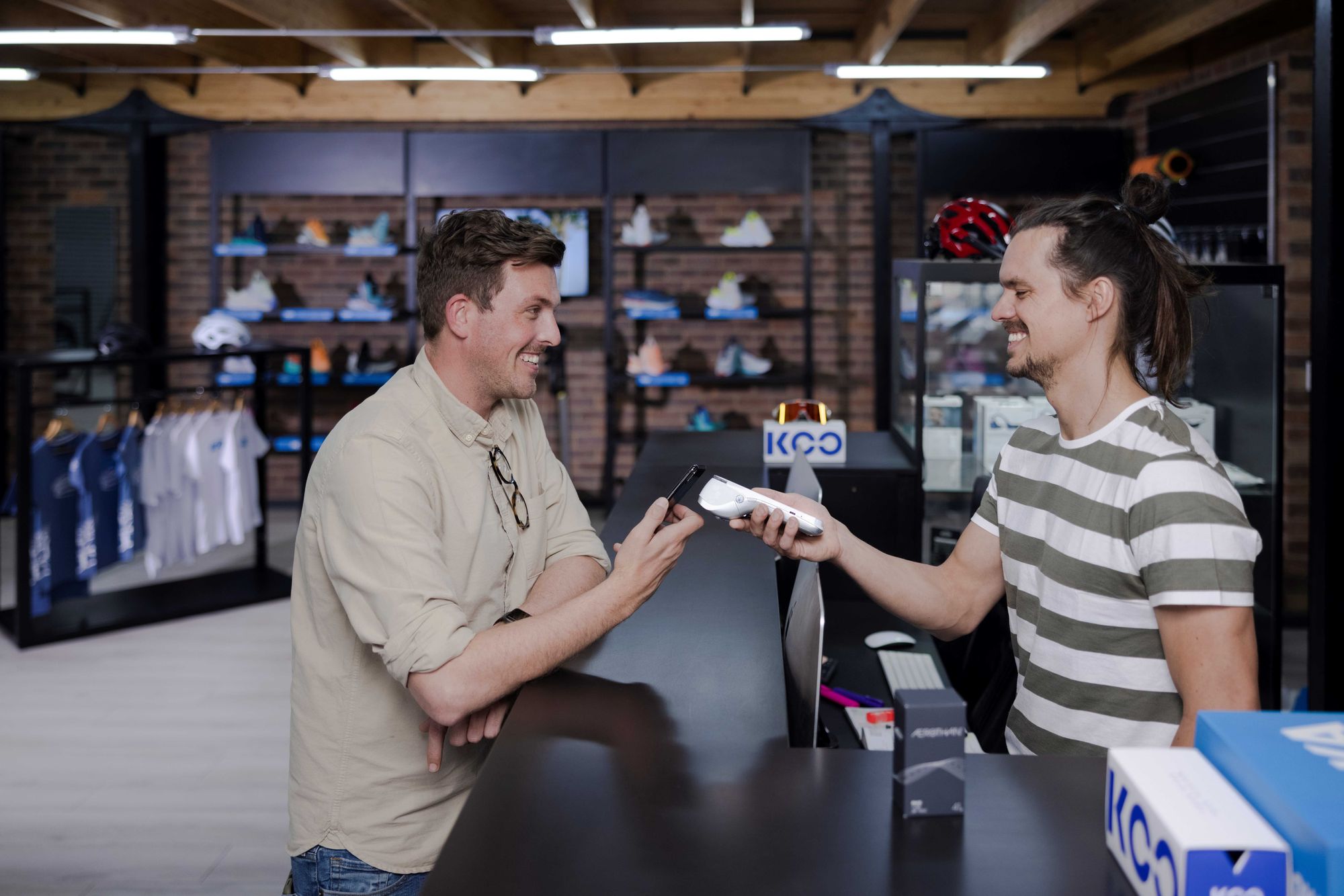 A customer at a sporting good store taps to pay on a handheld POS device