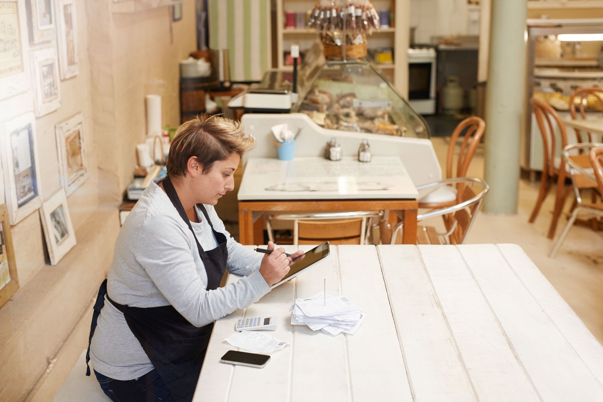 A shop owner looks at her payment processing bills on her tablet