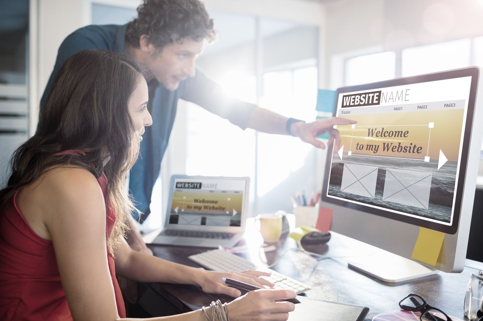 Man and woman at a desktop computer building a website.