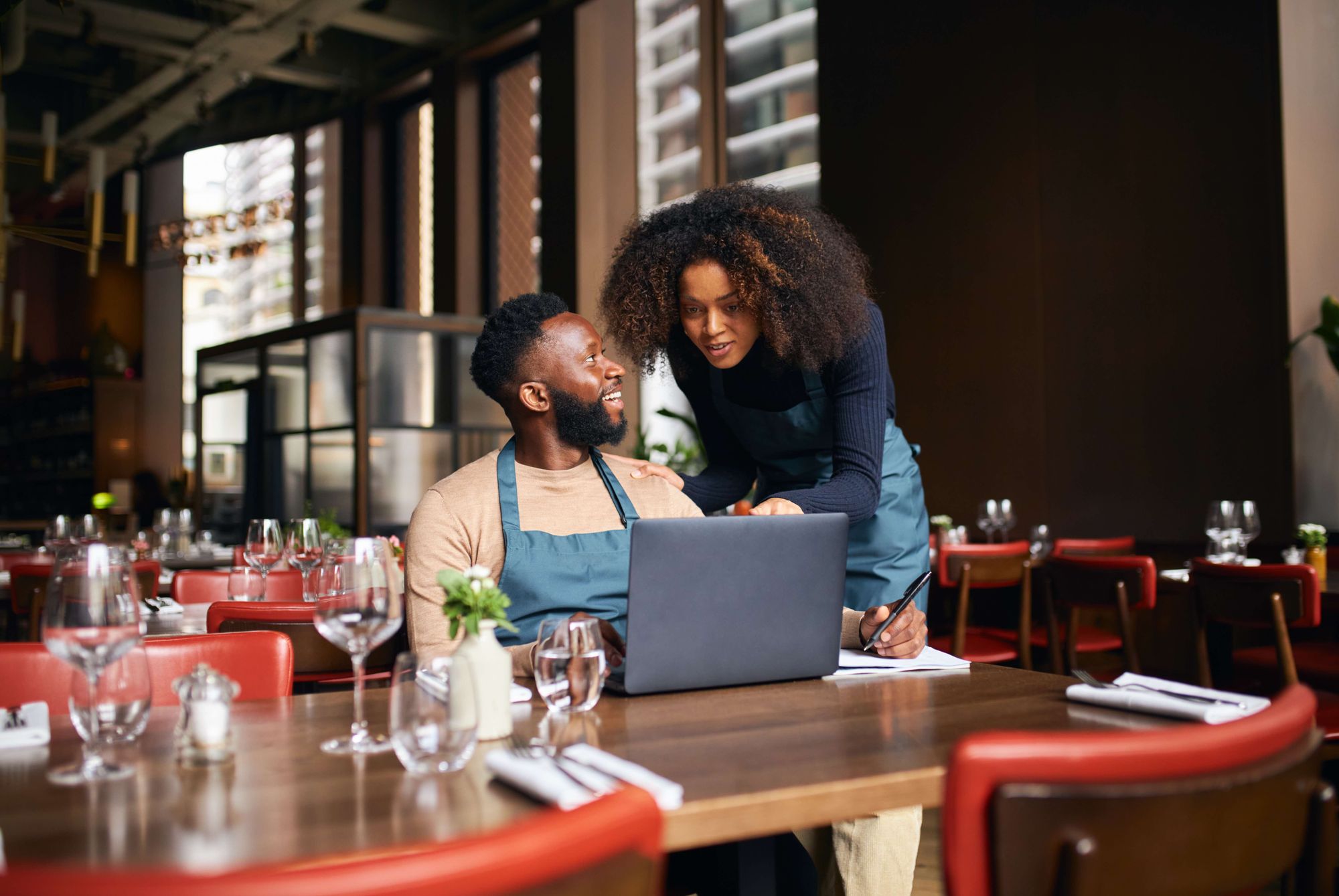 A man and woman are in front of a computer discussing their business plan.