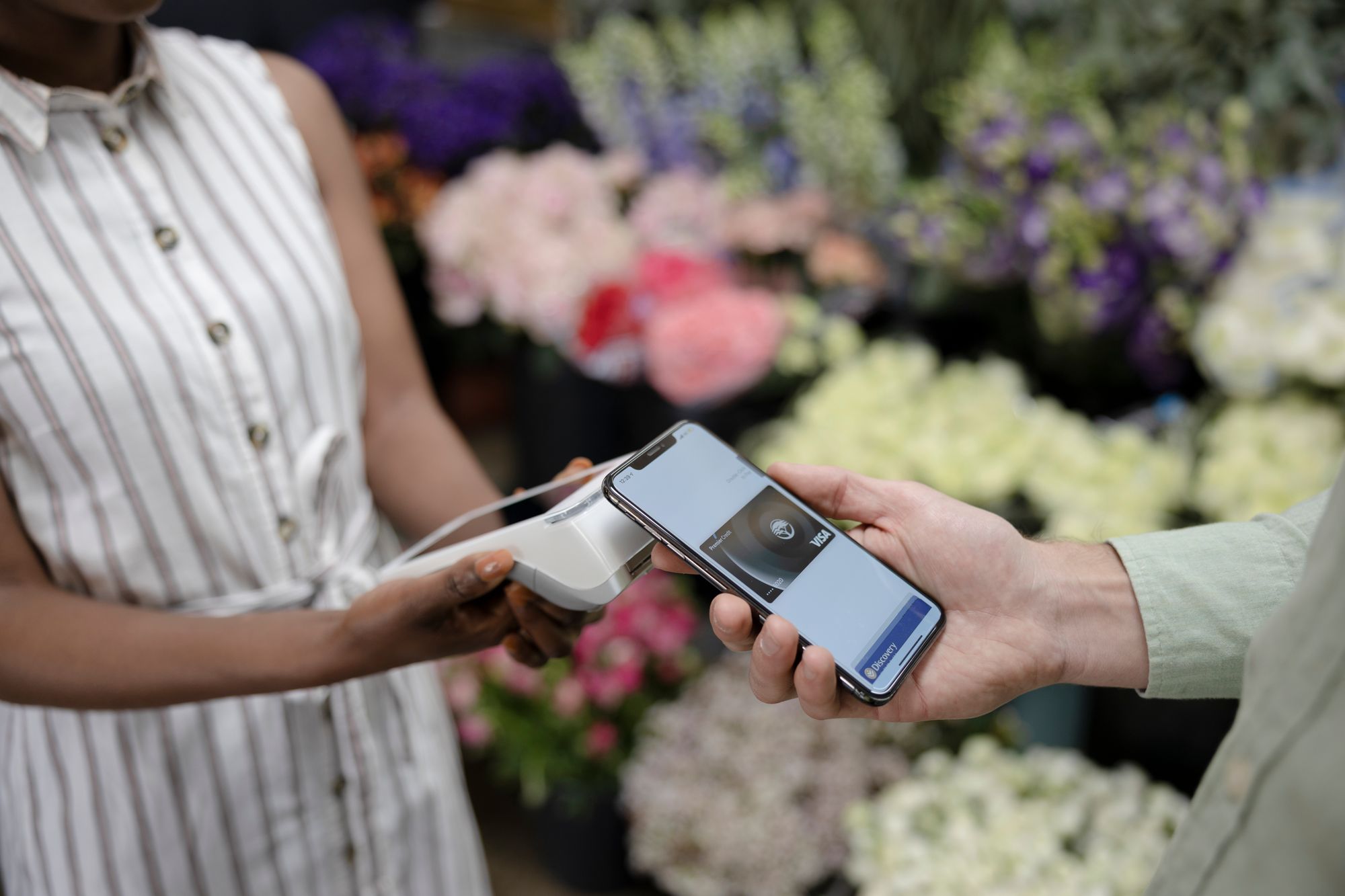Woman holding her smartphone to a handheld retail POS device to complete a transaction.
