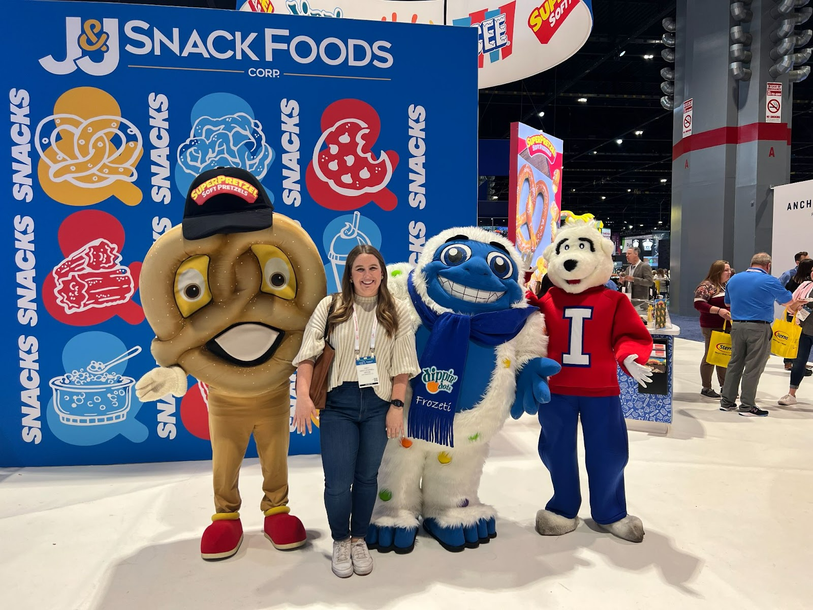 Nancy O'Connell at the 2023 National Restaurant Association Show, posing with a pretzel, Yeti, and bear mascot