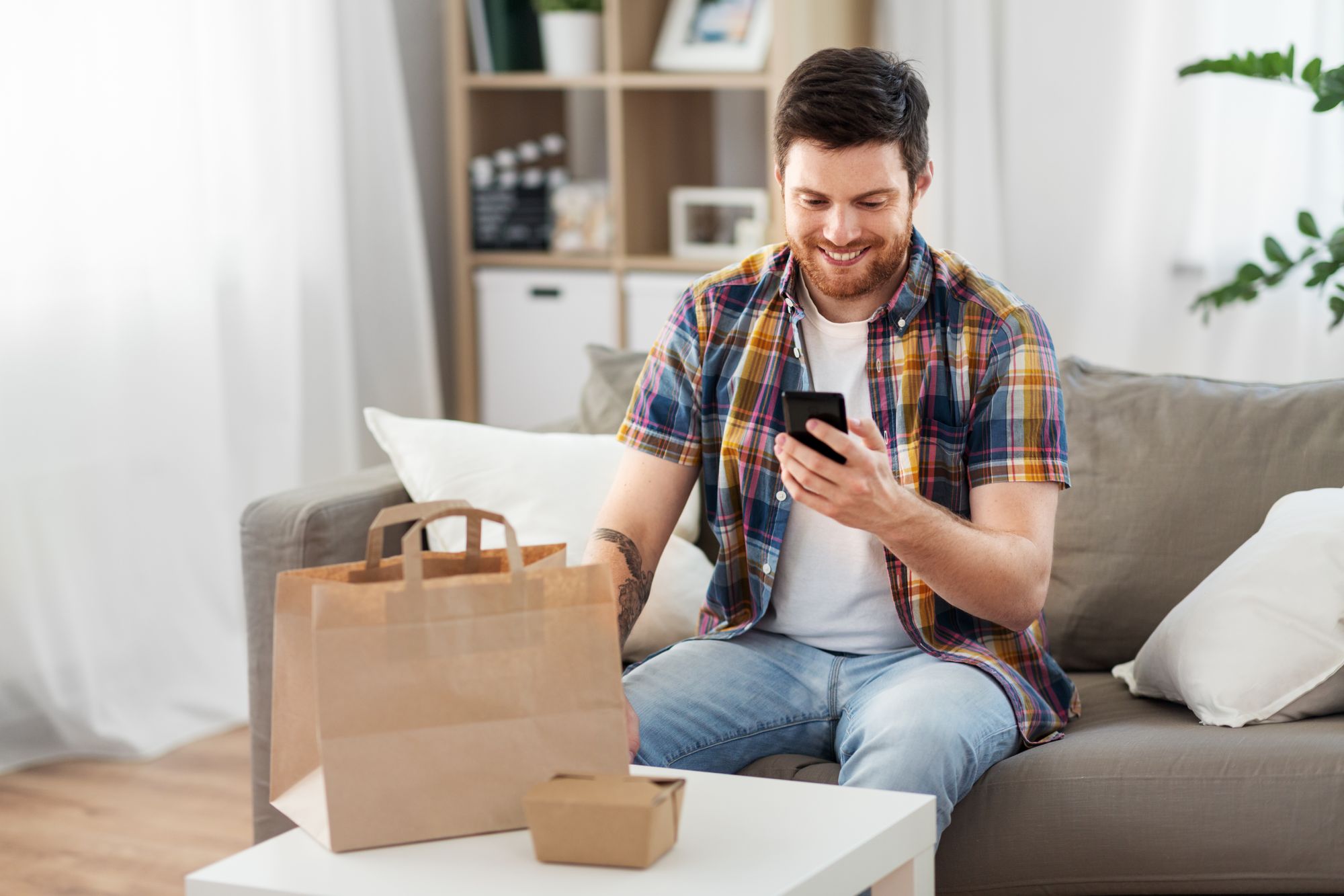 A guest enjoys their takeout food order while navigating their smartphone food delivery app.