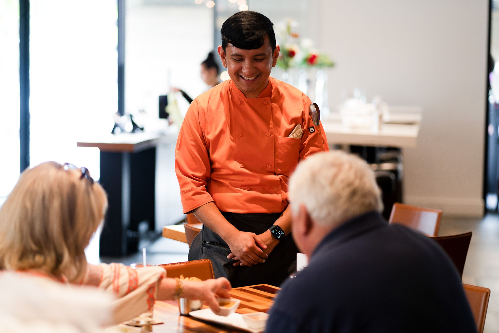 A server checks in on two customers at a restaurant