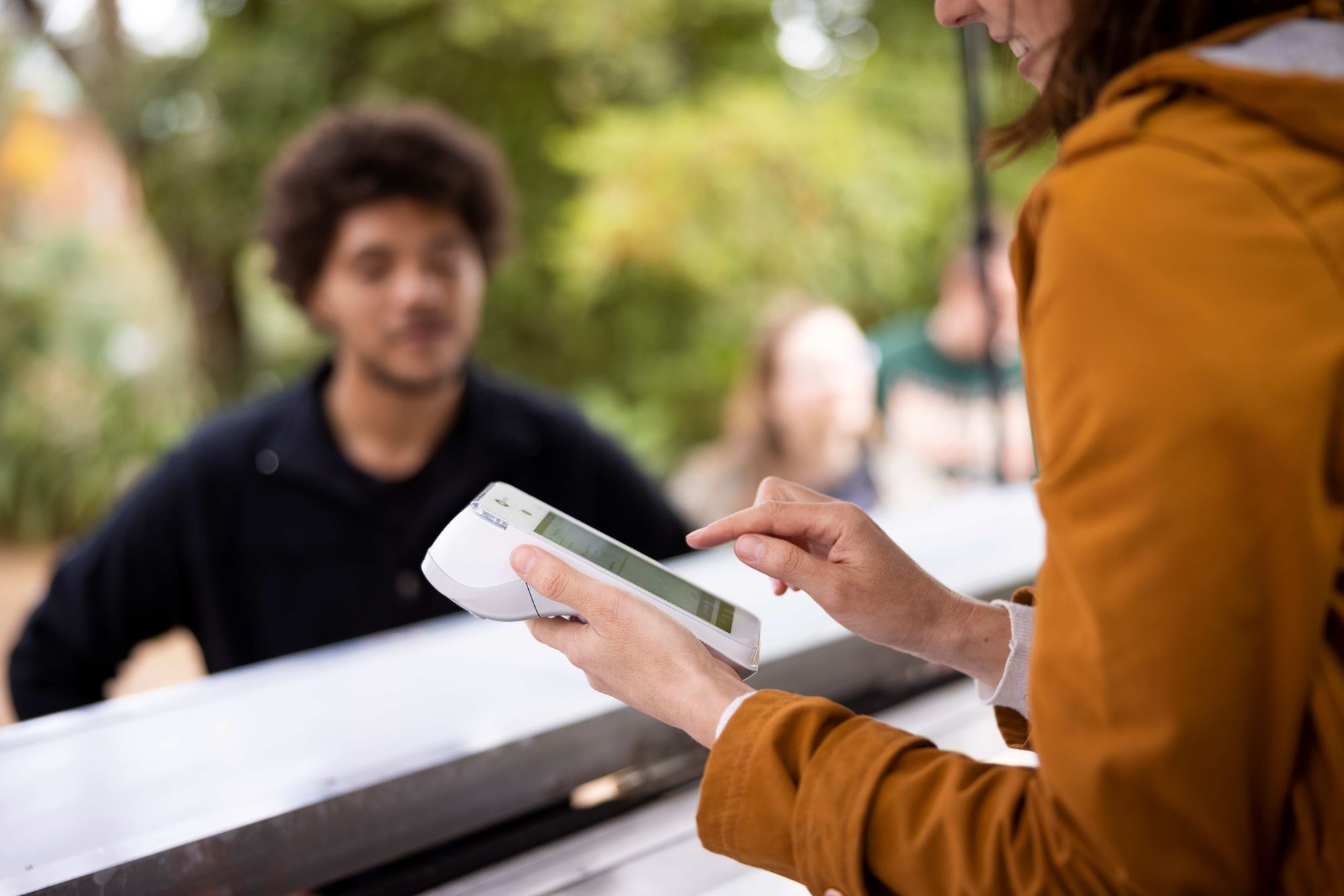 A restaurant worker types in an order on a handheld POS device at a pop-up restaurant