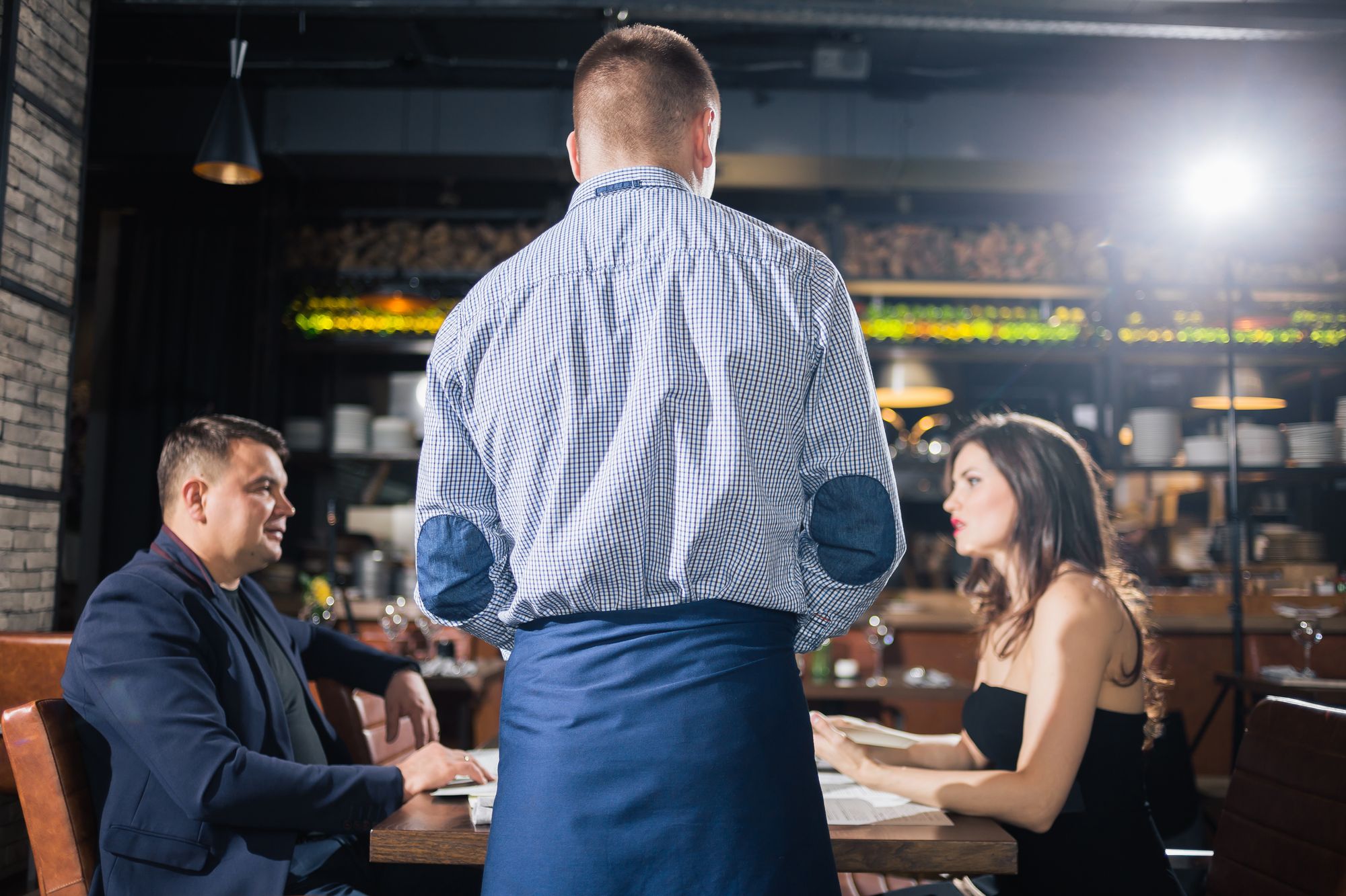 Restaurant staff serving two guests eating dinner at a restaurant.