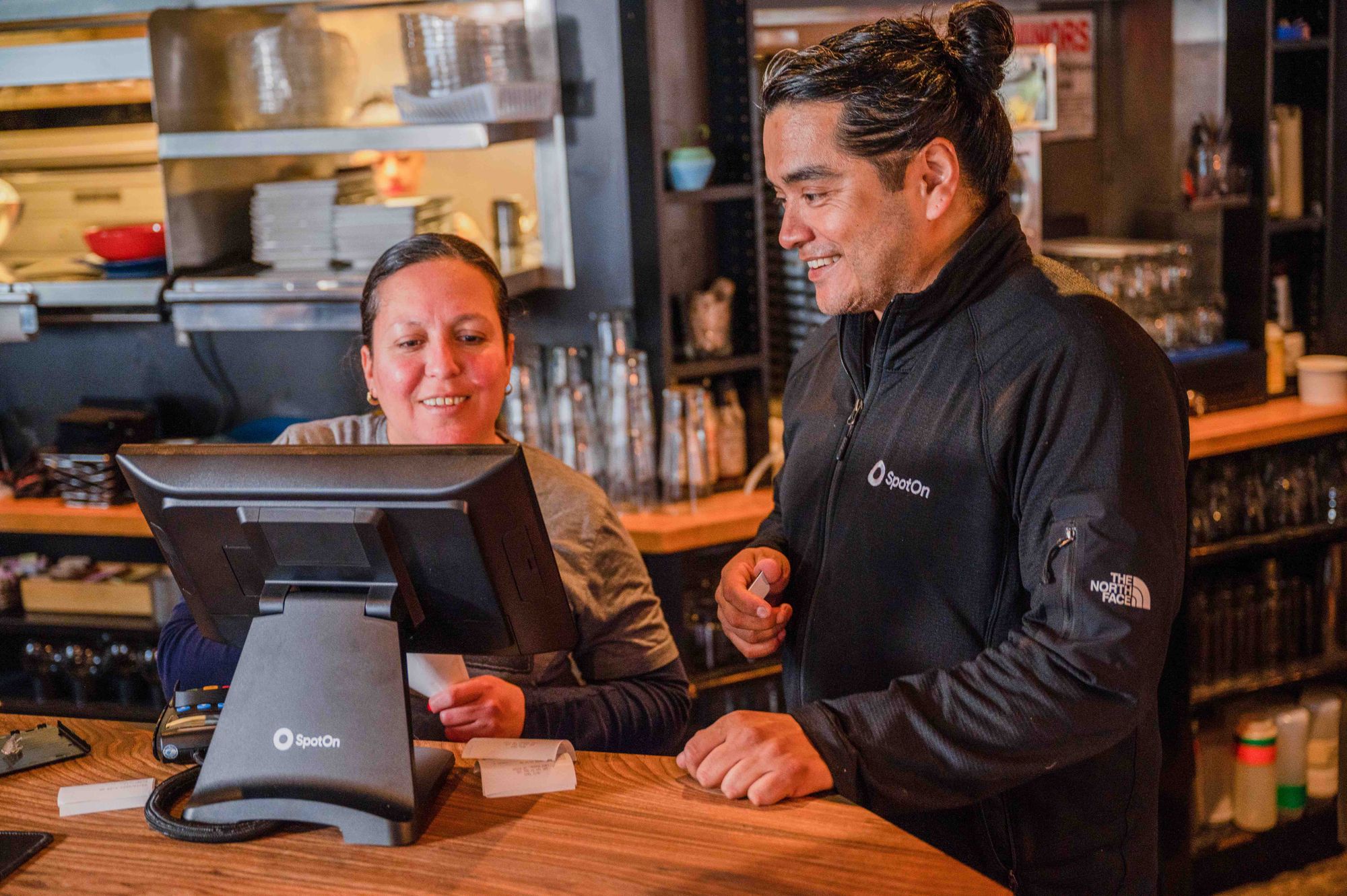 A POS representative shows a restaurant worker how to use the station.