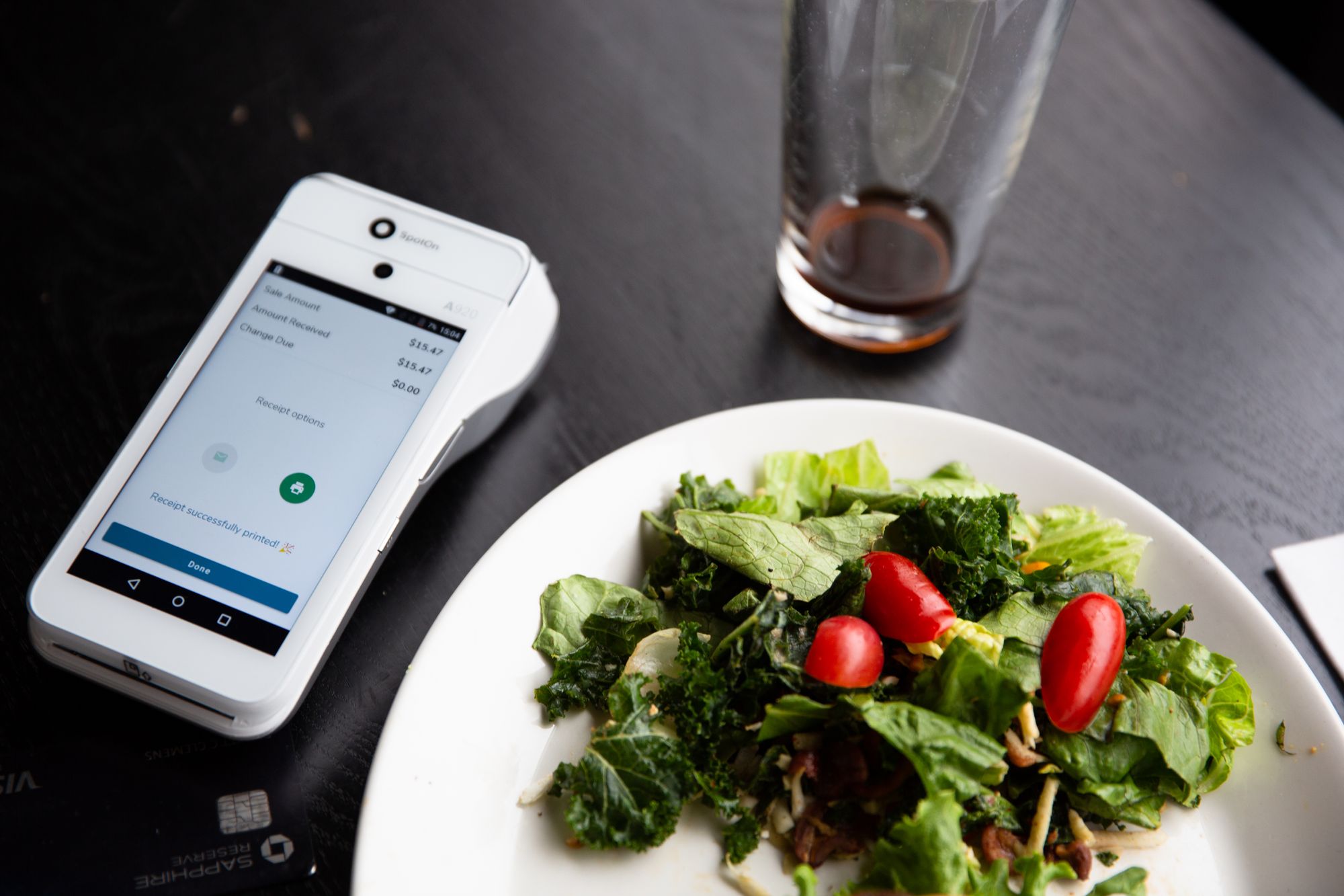 Spoton handheld POS system next to a restaurant salad.