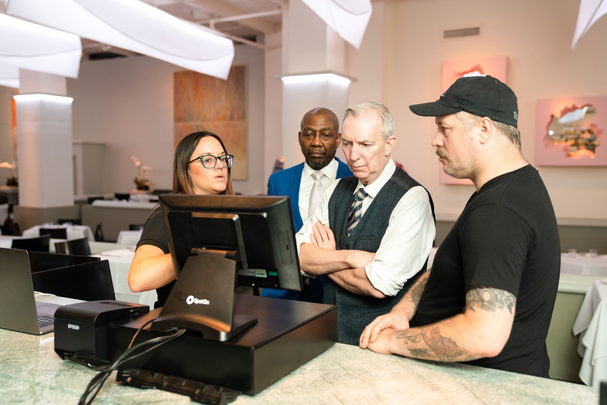 Two restaurant staff members watch a tutorial with two SpotOn on-site implementation specialists.