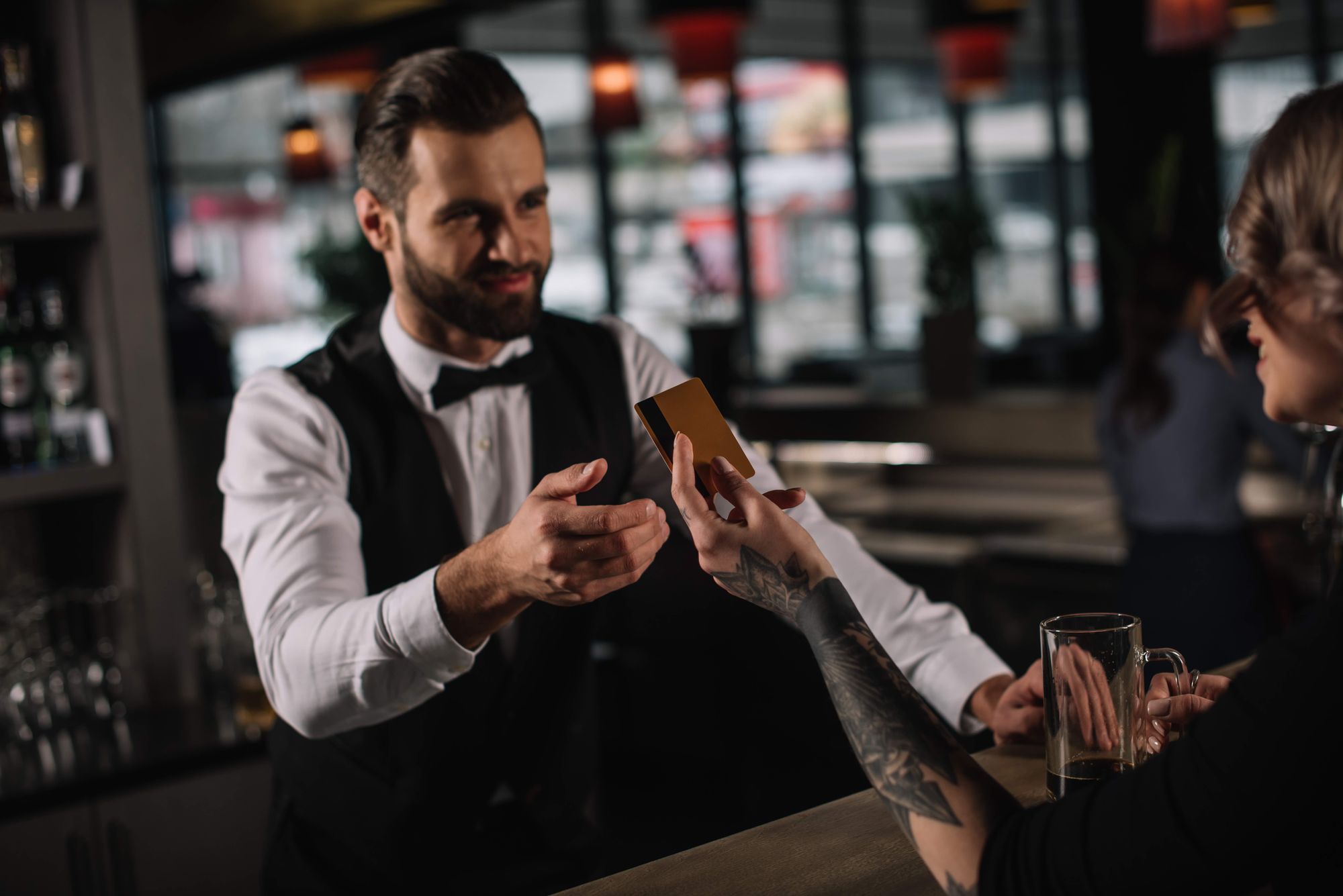 A bartender receives a credit card from a woman customer.