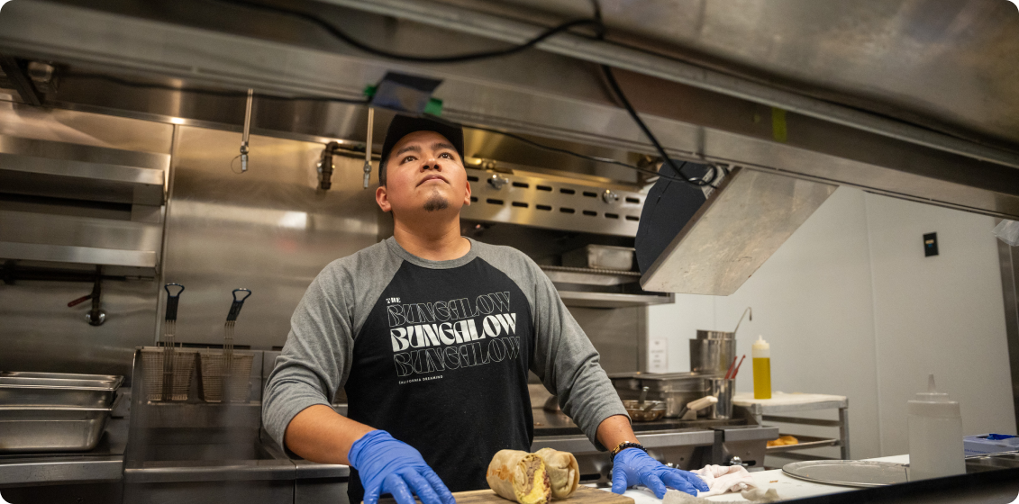 A cook looks up at a kitchen display system to get details on the order he's preparing