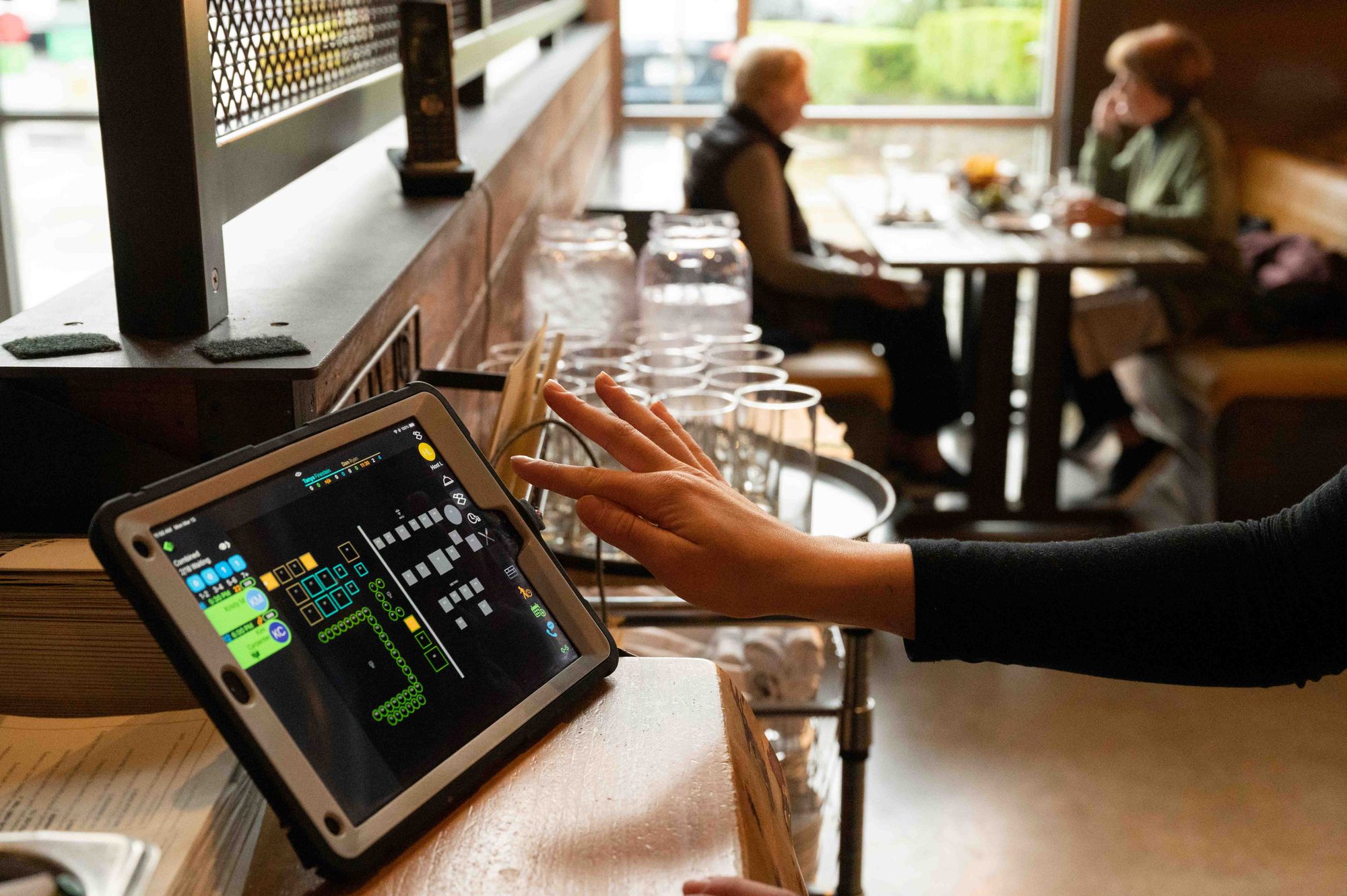 A host checks guests in using a digital waitlist tablet