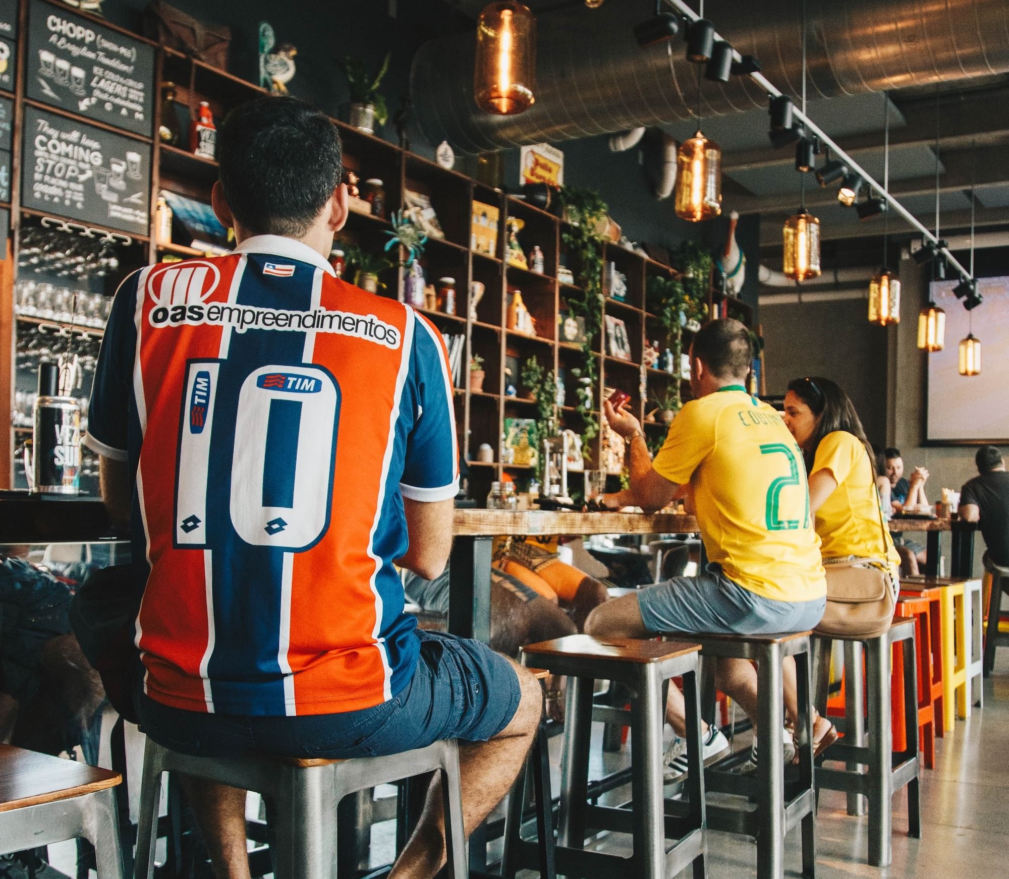 Bar patrons sitting on bar stool sports in a bar pub on game sports night drinking beer.