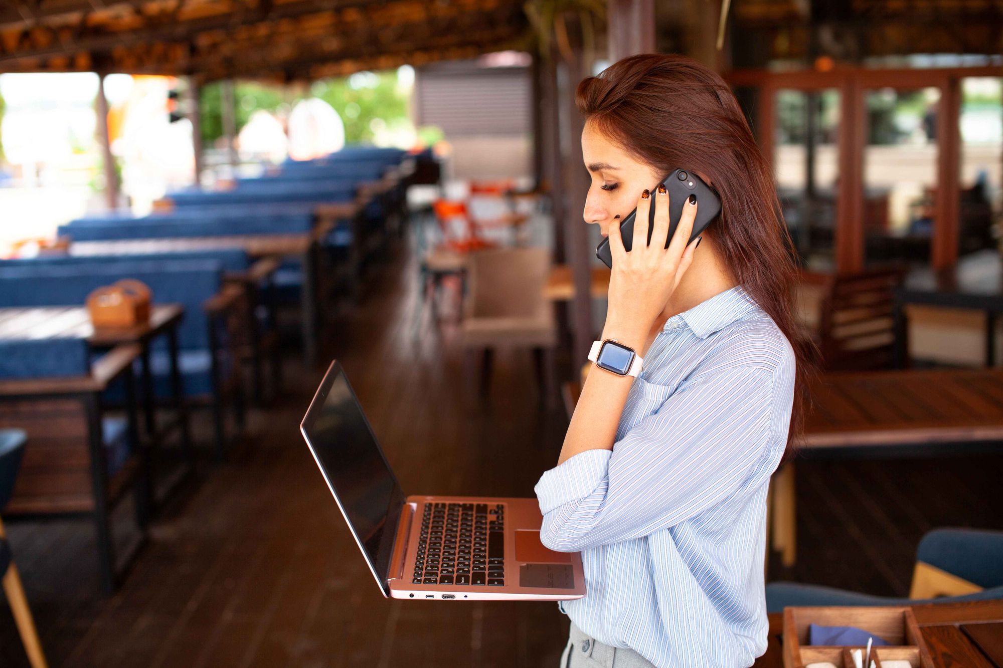 A restaurant manager on a laptop is on a phone