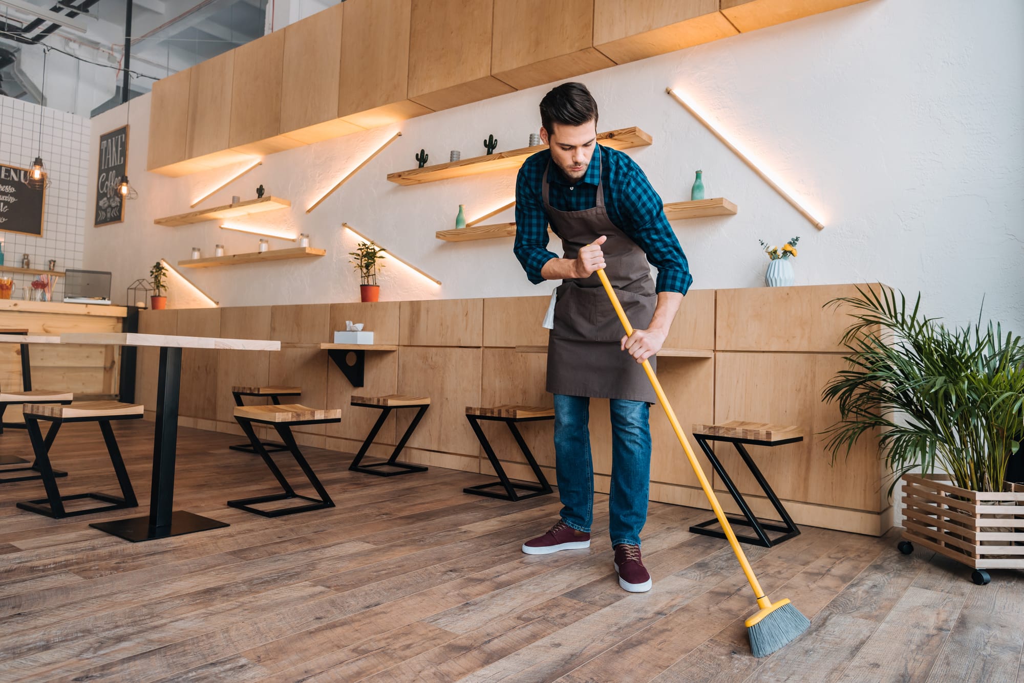 A man sweeps in an empty restaurant.
