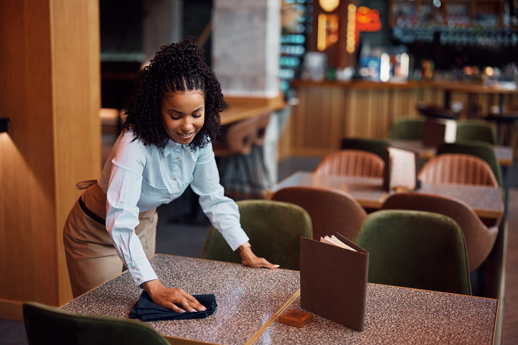 Woman wipes a table in an empty restaurant.