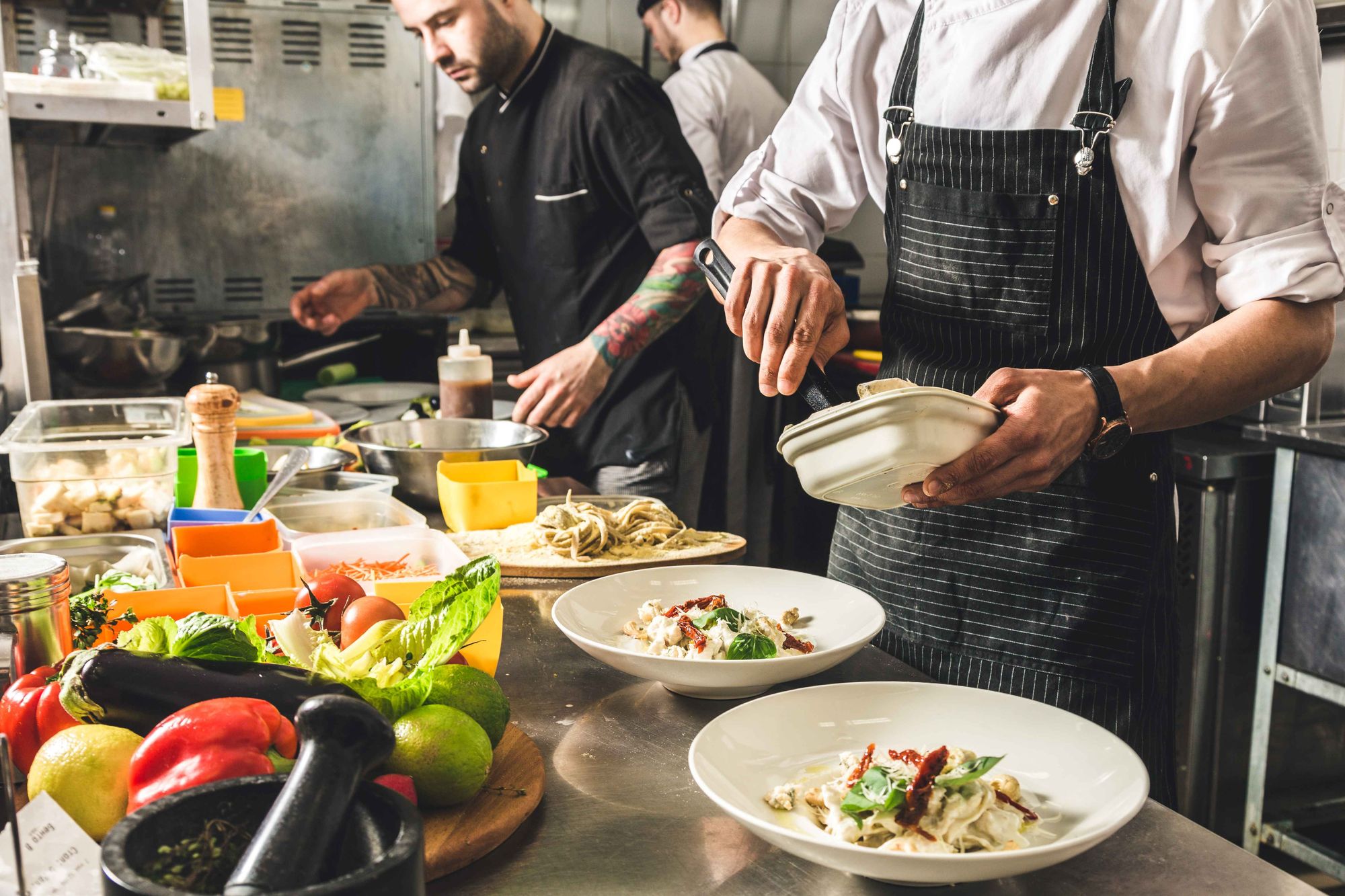 3 cooks prepare food in a restaurant kitchen