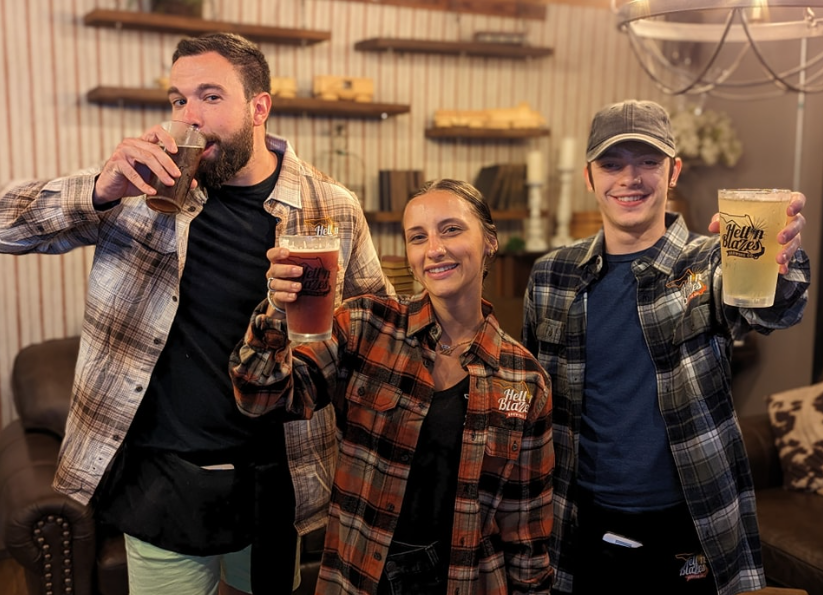 Three employees at Hell N' Blazes Brewiing Company hold up their beers