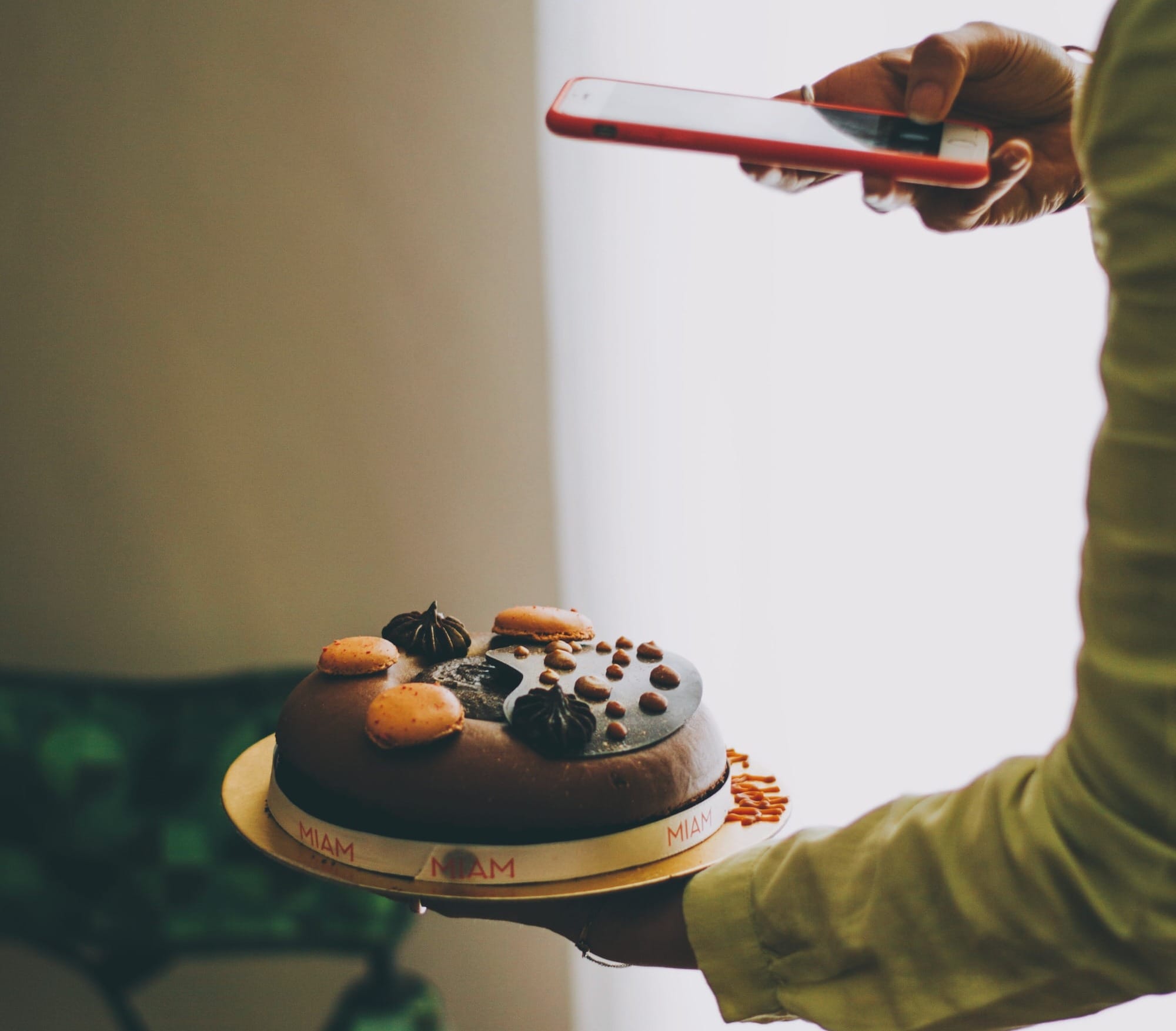 Restaurant dessert chef holding a Willy Wonka cake and taking a photo for Instagram.