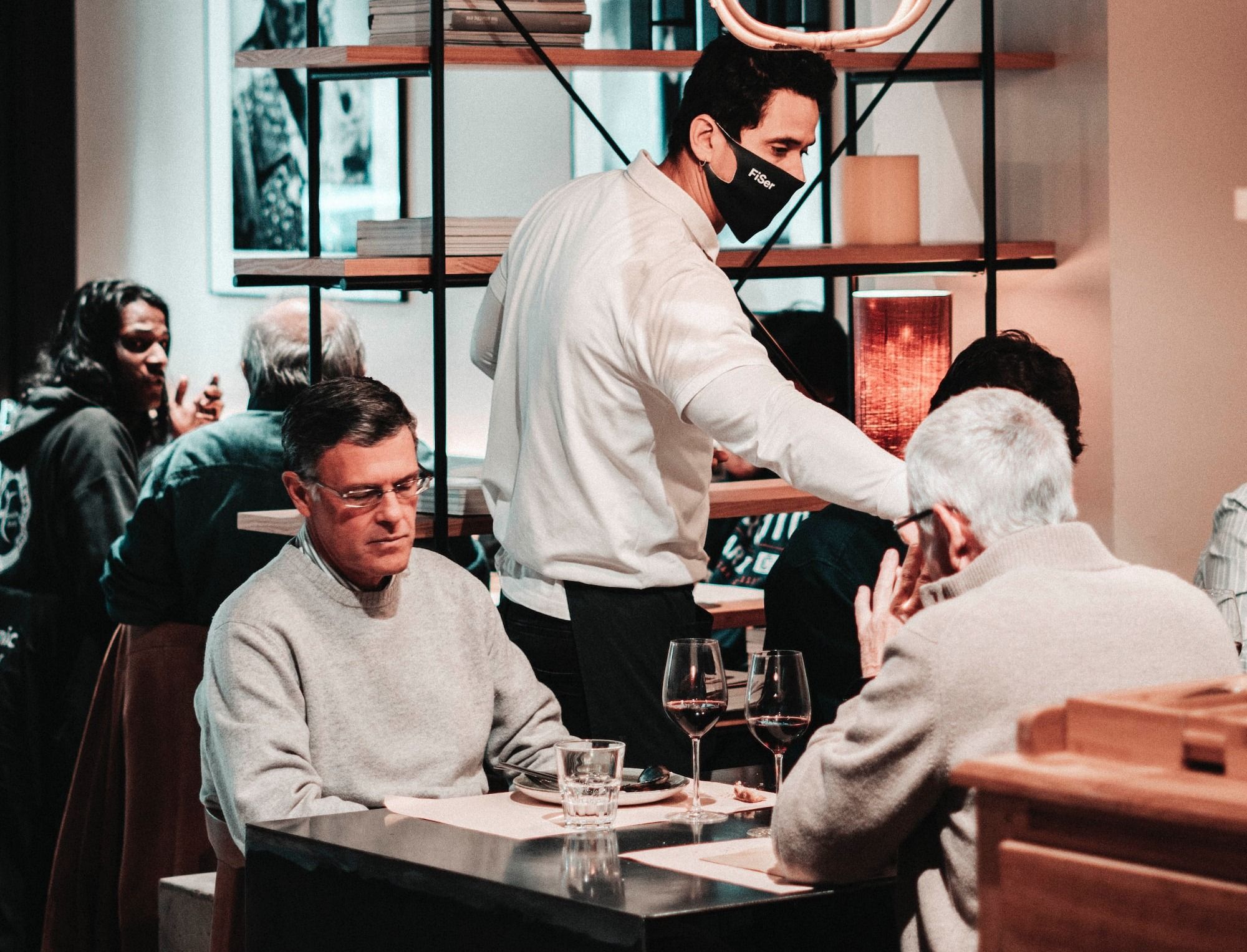 Restaurant guests sitting with wine at a table as they wait for their food.