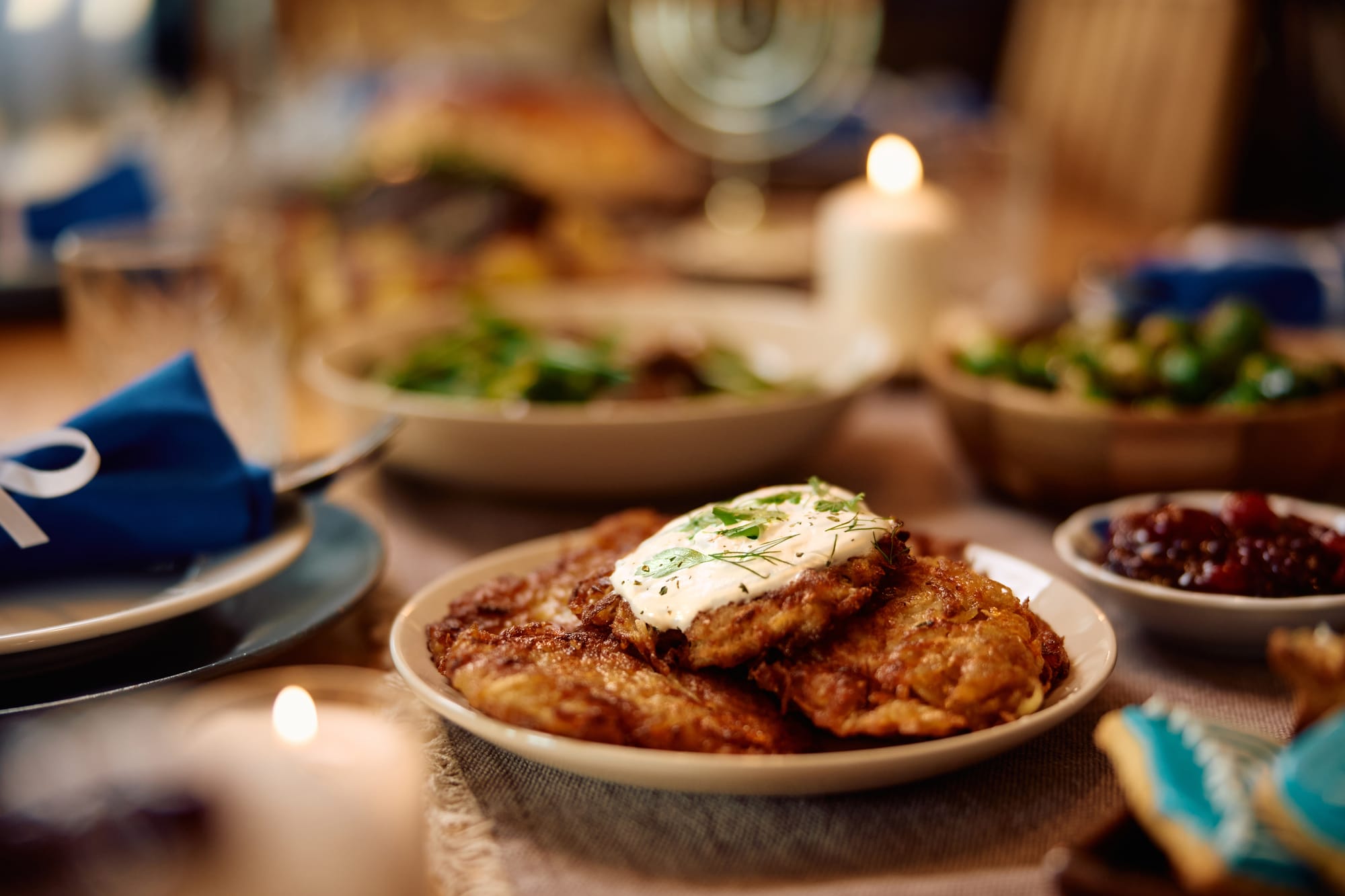 A fully set dinner table with a plate of latkes front and center