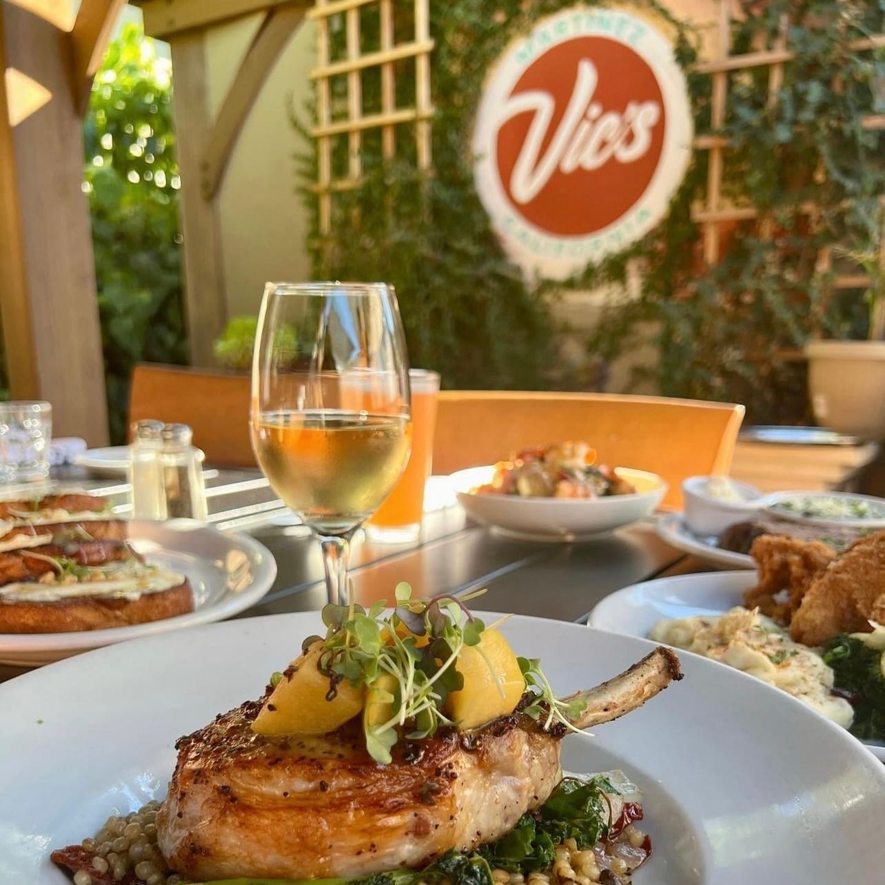 A table at Vic's Martinez with plated food and a glass of white wine
