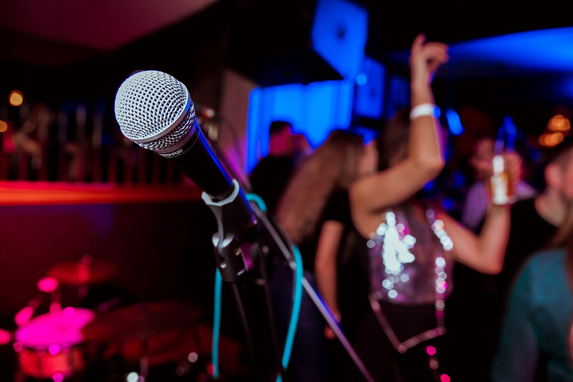 The view from in front of a microphone of happy bar guests dancing