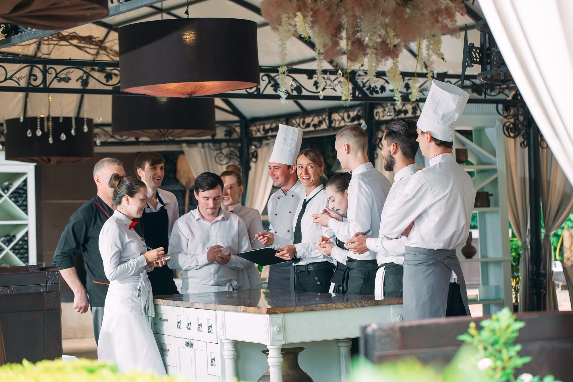 Restaurant manager and his staff interacting with the head chef at a restaurant.