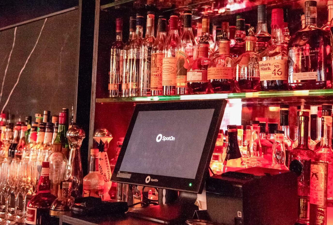 SpotOn point-of-sale system on a bar counter with different drinks in the background.