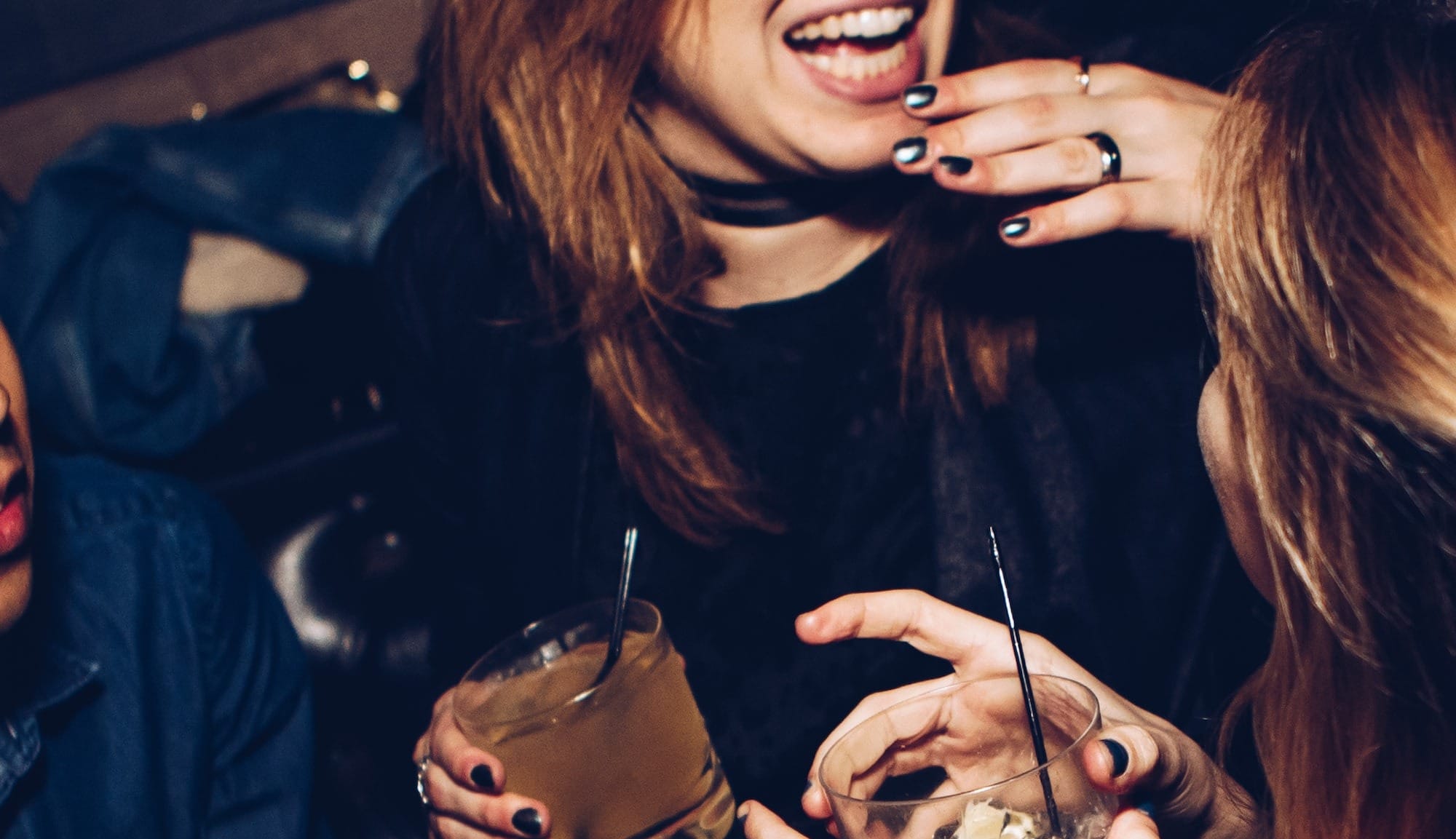 two women talking while holding drinking glasses