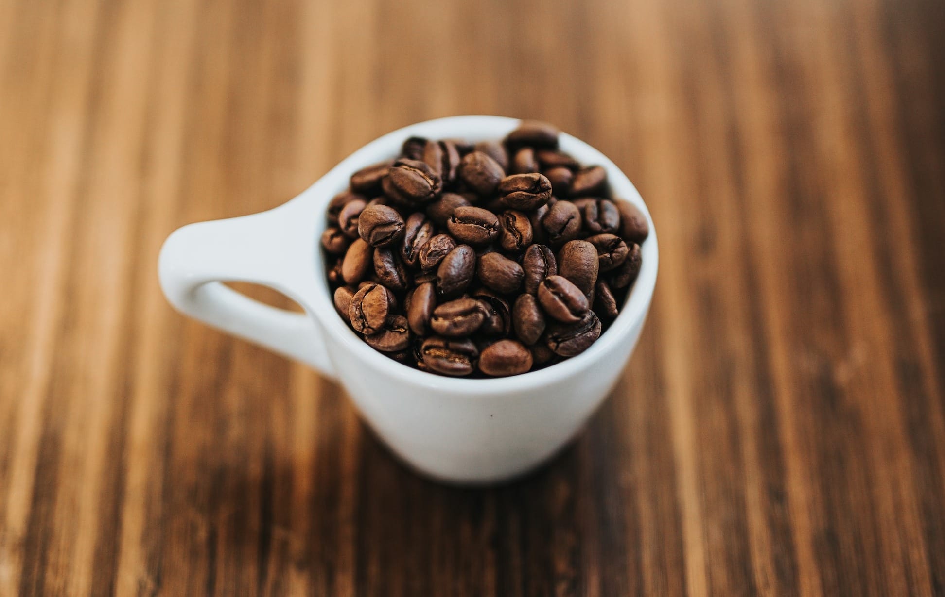 Round white ceramic mug with coffee beans.