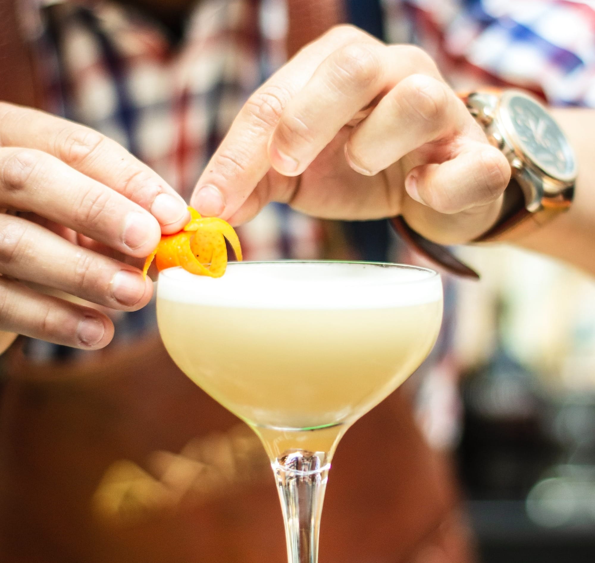 Bartender preparing a delicate Christmas cocktail with an orange peel.