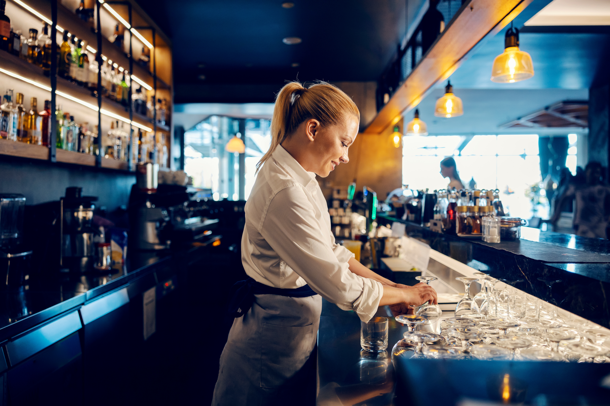 A barback cleans glasses before a shift. 