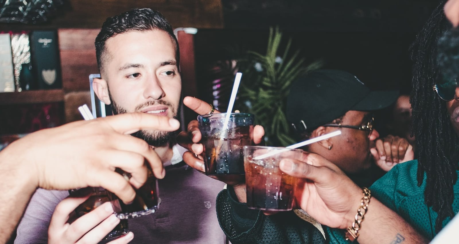 three people holding glass bottles while talking during happy hour at a bar